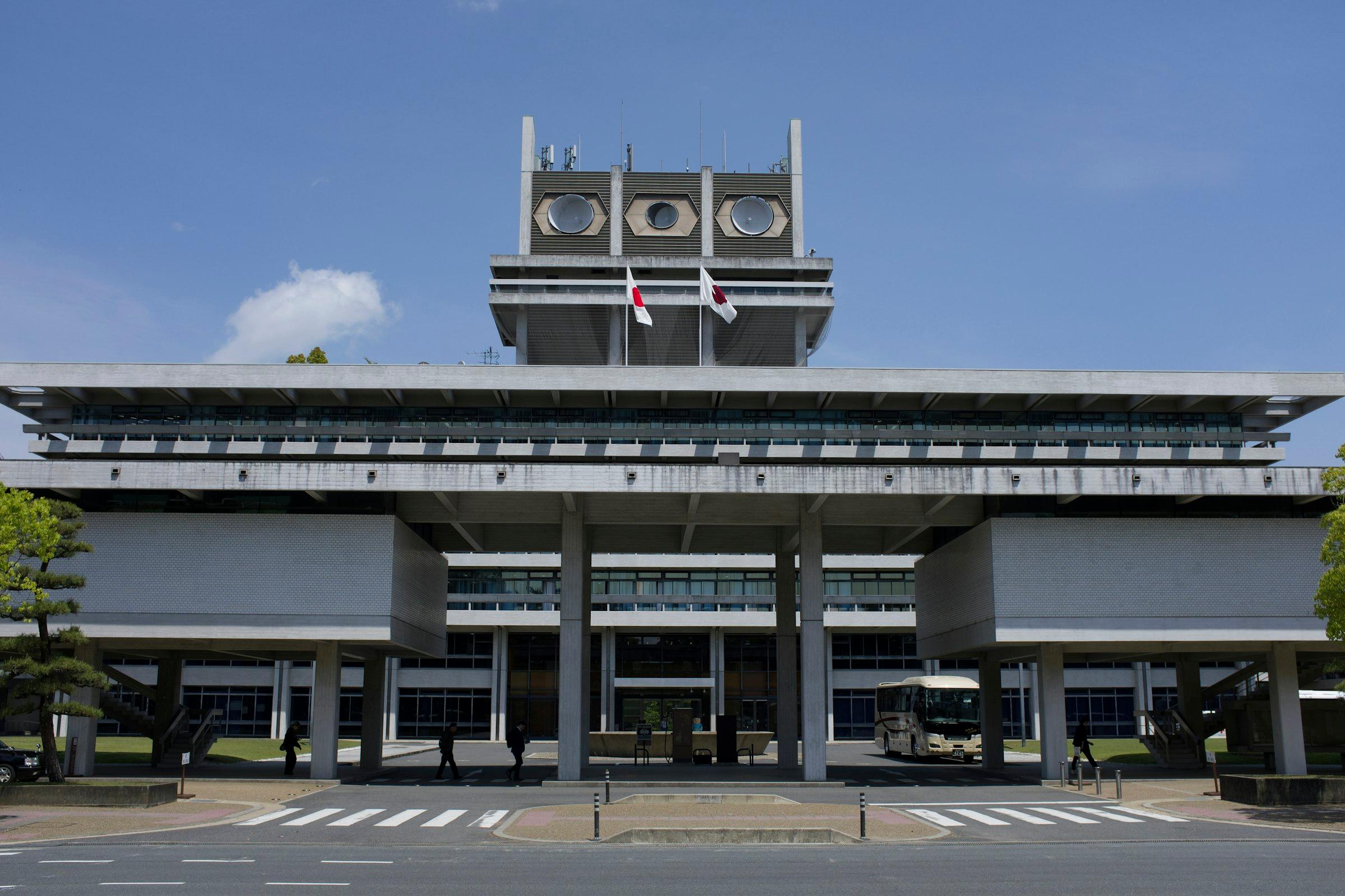 Modern grey building with flags under a clear blue sky