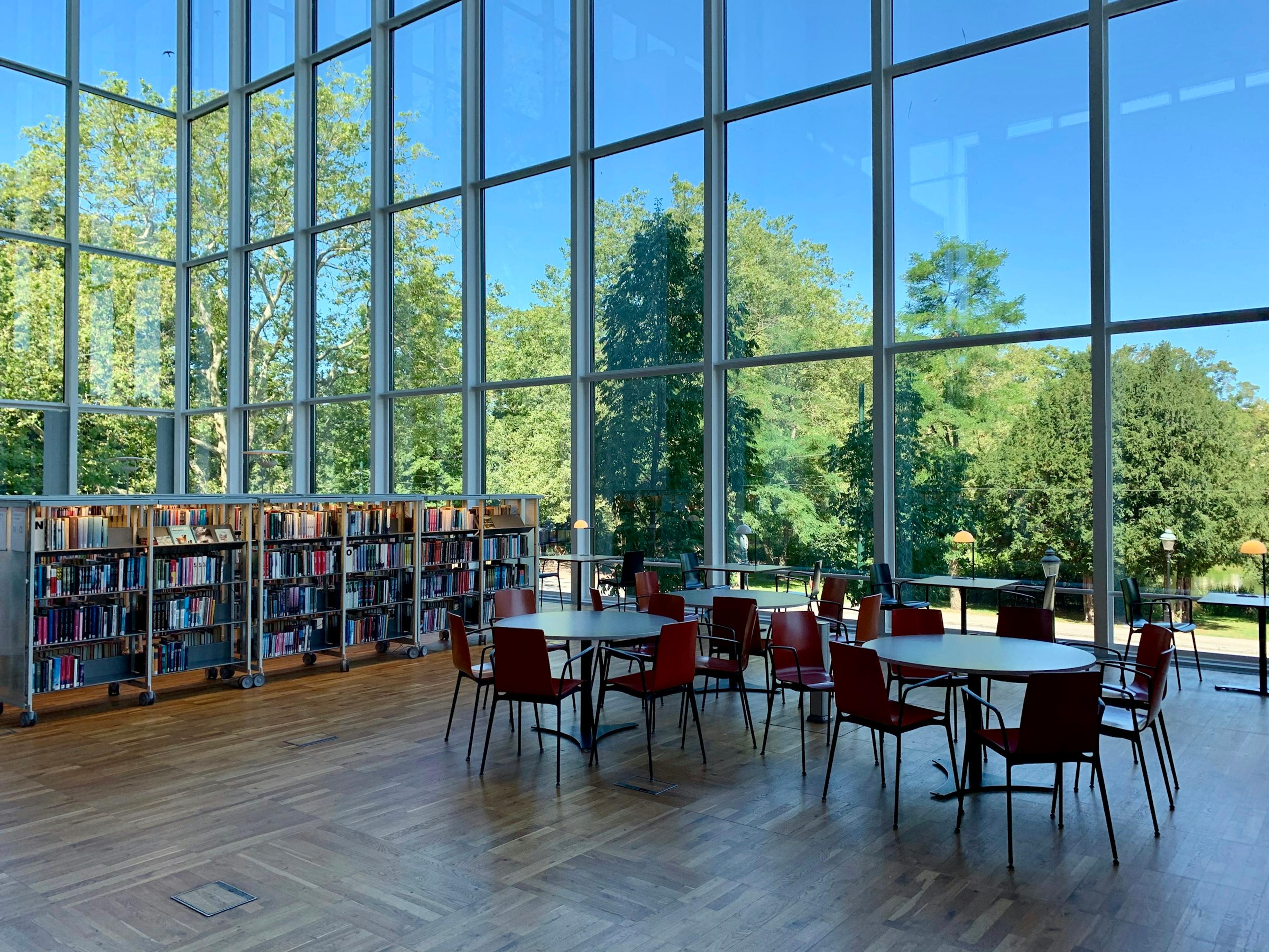 A library interior with tall windows, bookshelves and reading tables