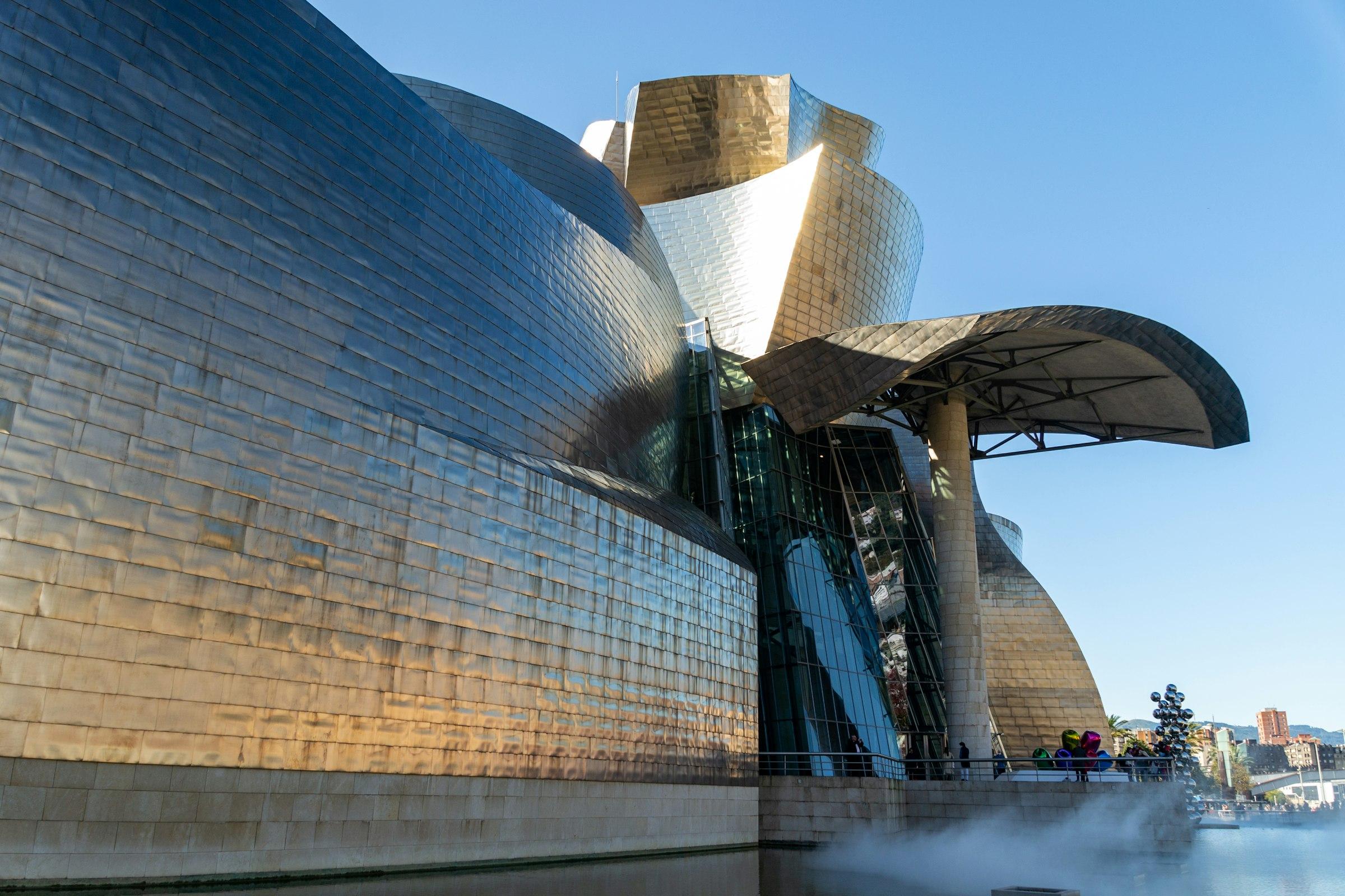 A large building with an exposed metal structure beside water