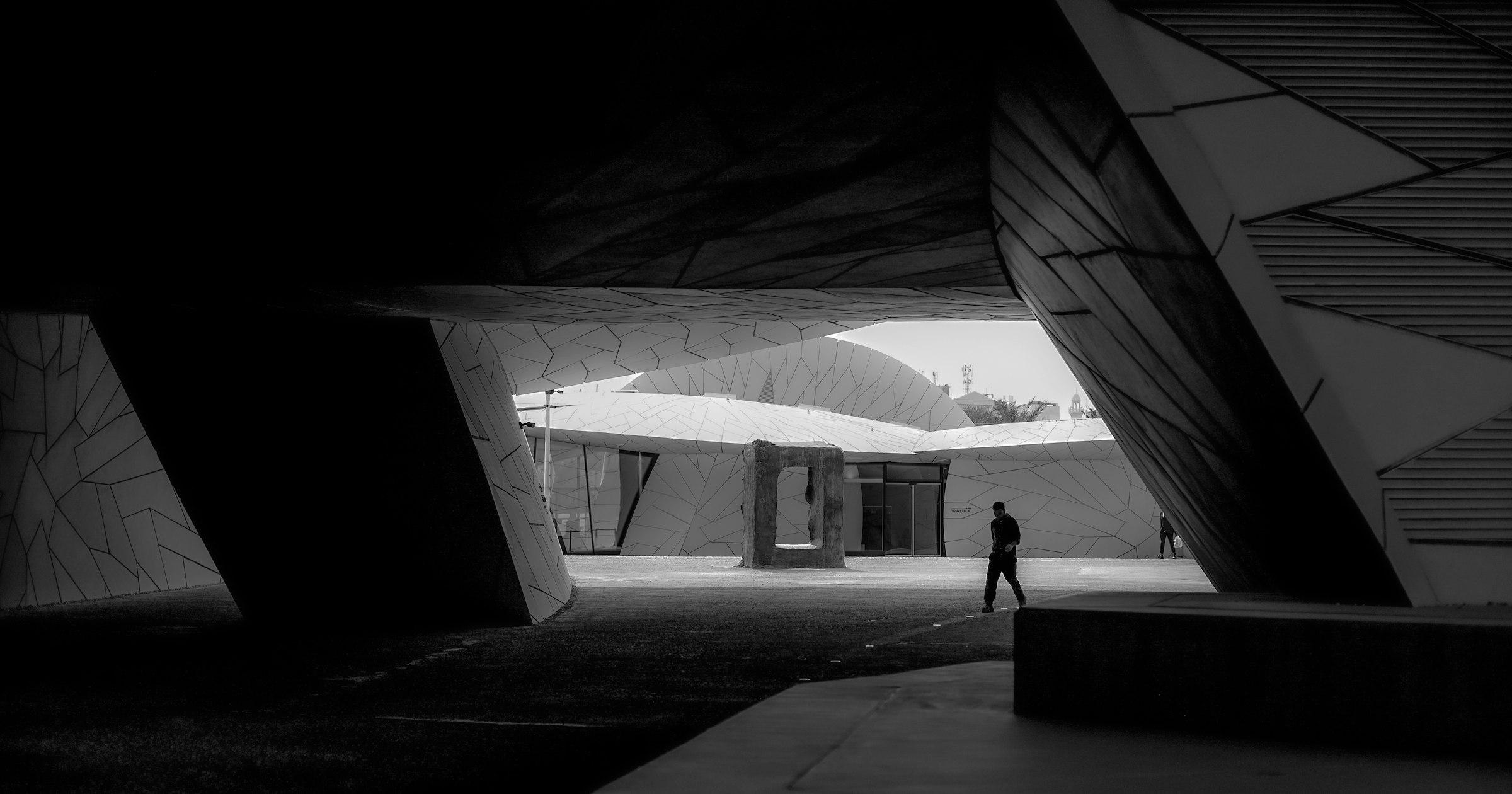A lone figure walking through a stark modern architectural space