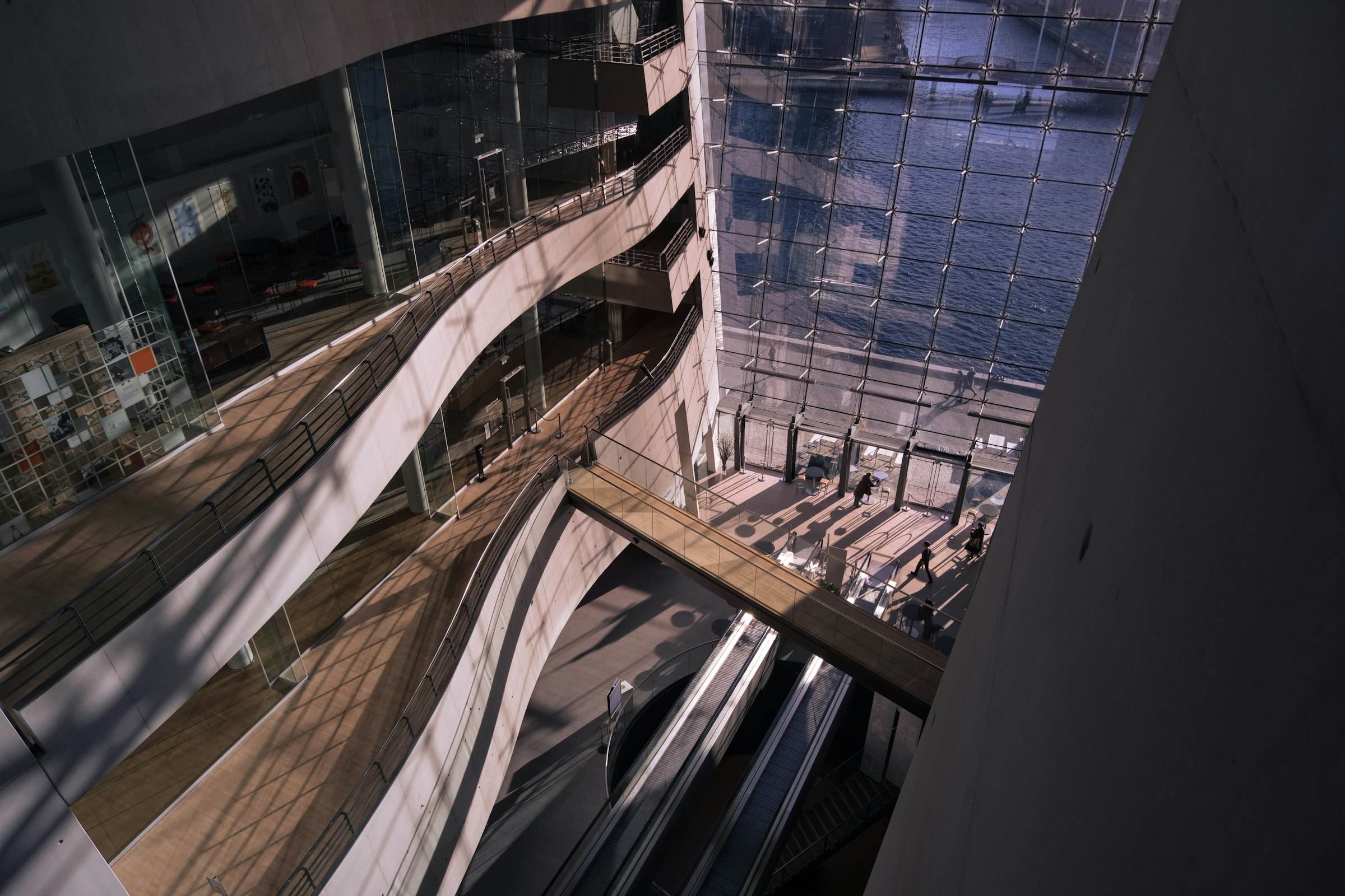 A modern atrium with curved balconies and a bridge over escalators