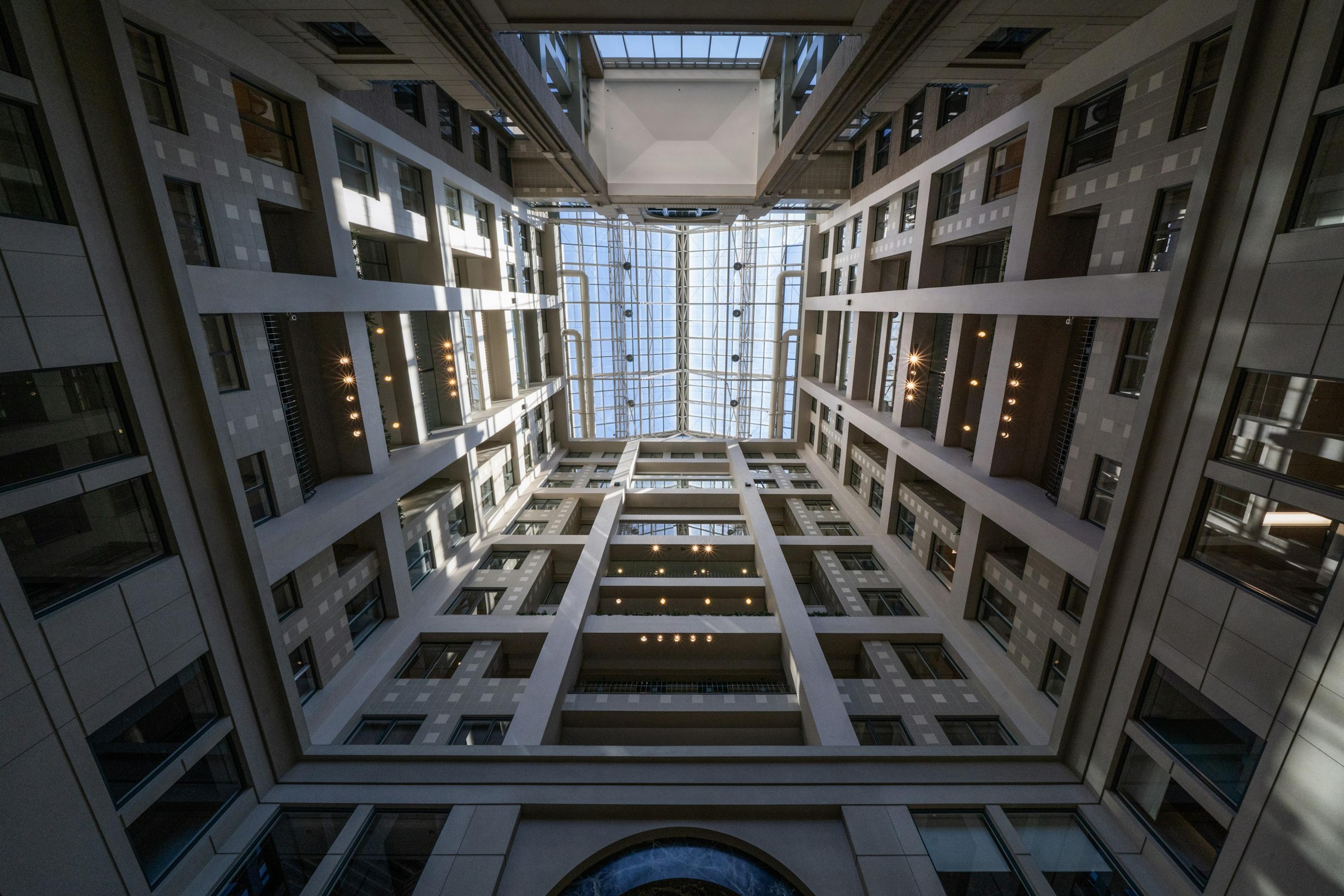 A symmetrical atrium with a glass skylight, seen looking upwards