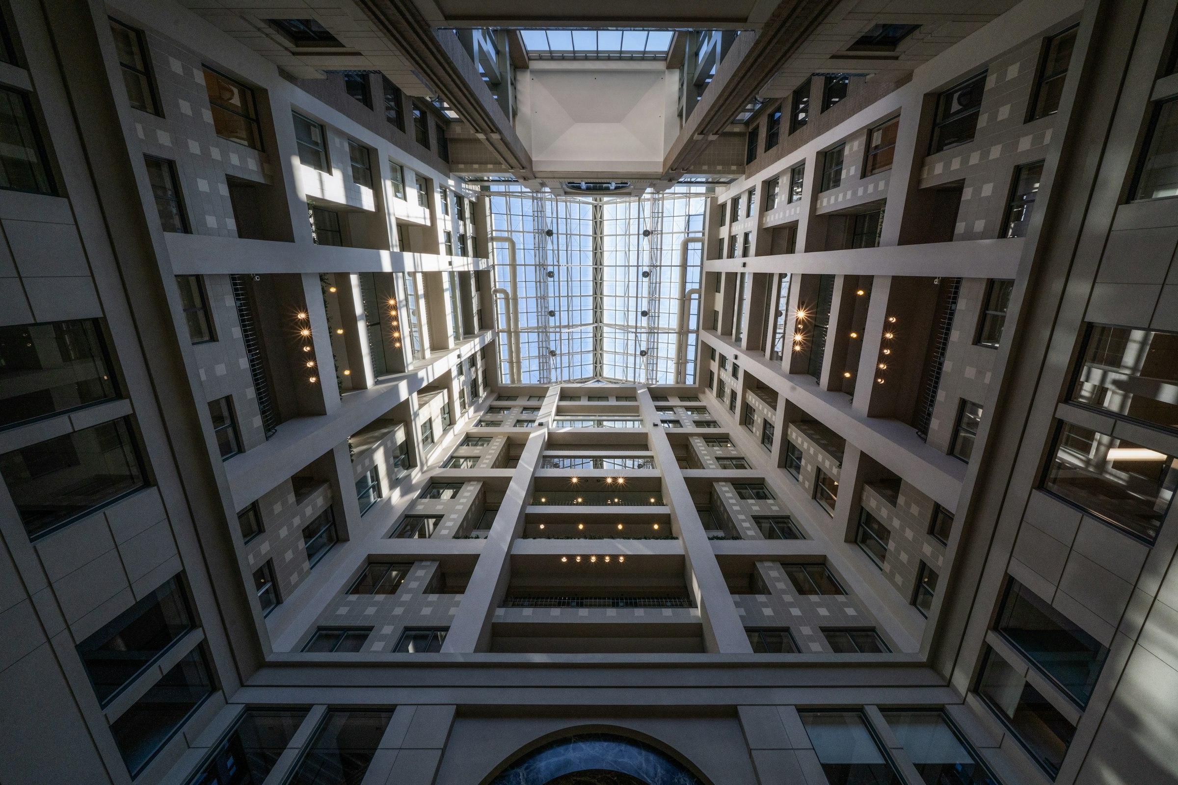 A symmetrical atrium with a glass skylight, seen looking upwards