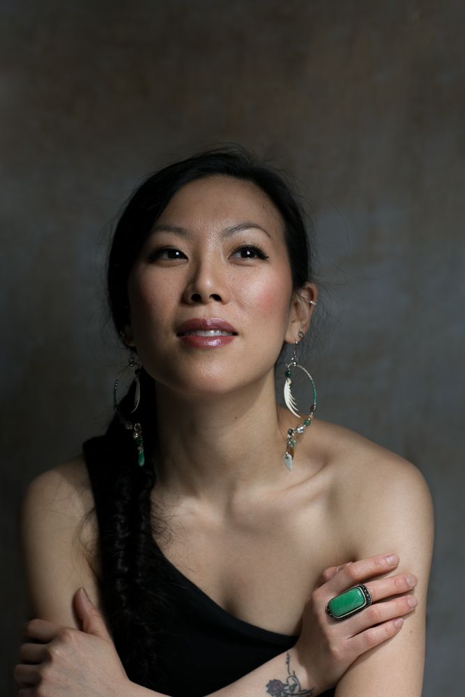 east asian woman headshot against a brown and gray background