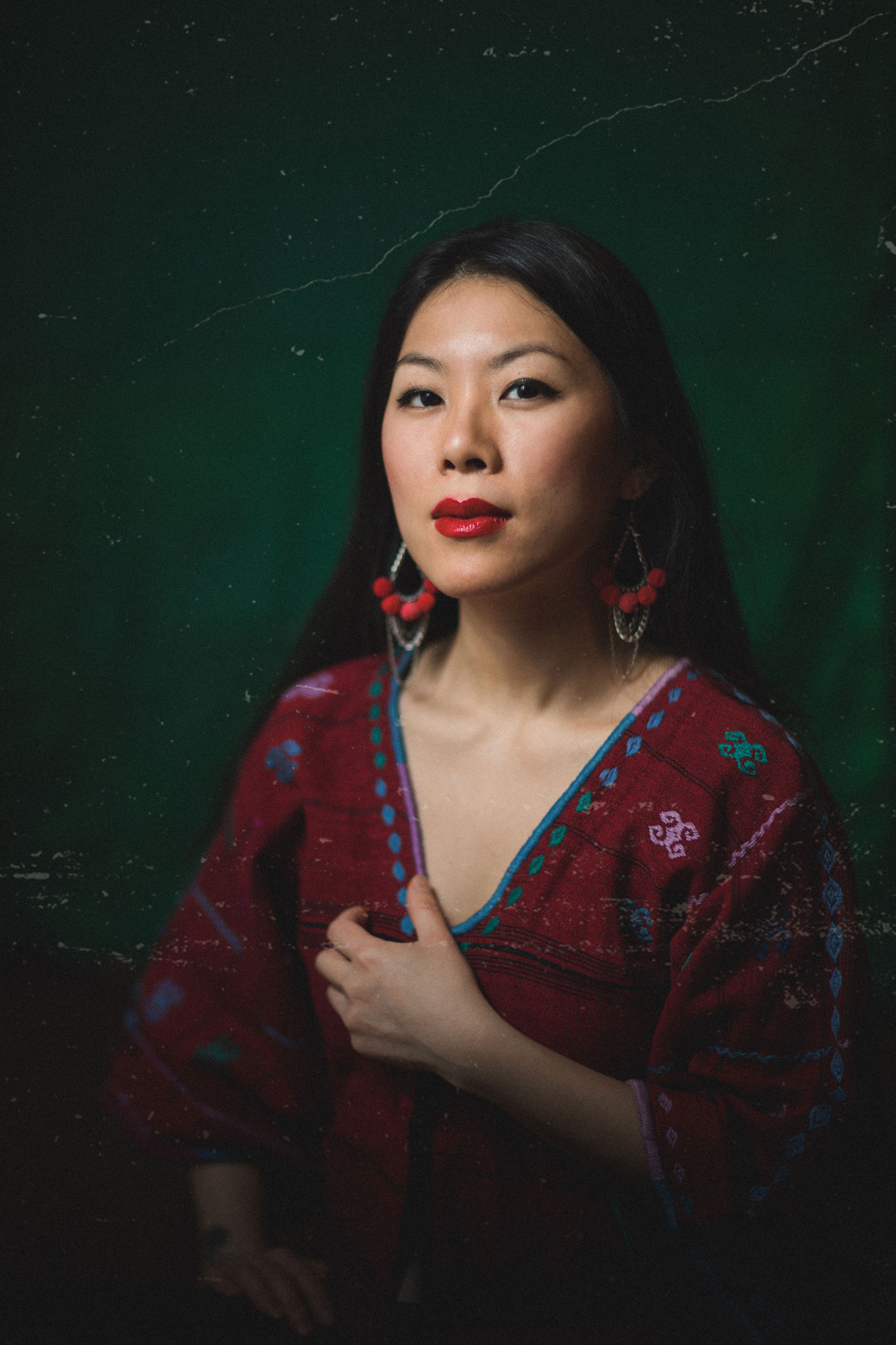 east asian woman in red against a green background