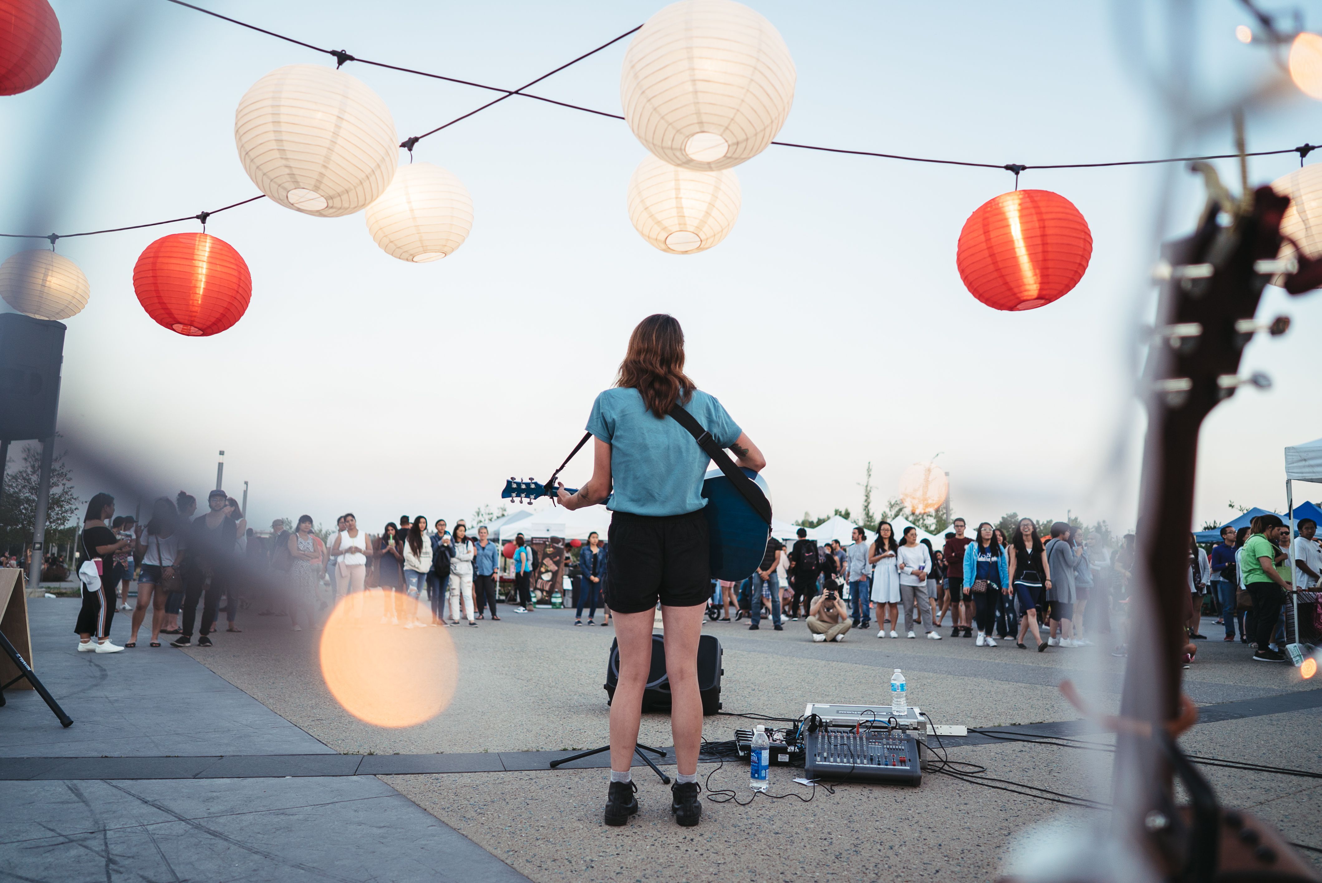 Person playing guitar in front of a crowd outside