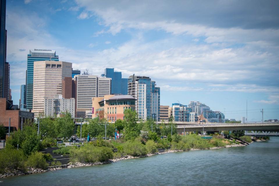 A photograph of the bow river in the foreground and East Village buildings in the background.