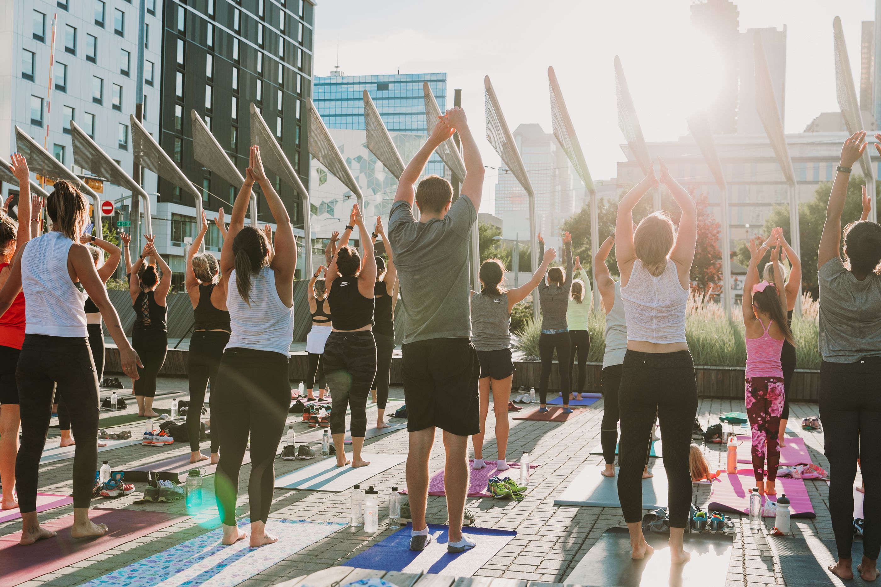 Many people practicing yoga together in the park in Calgary's East Village