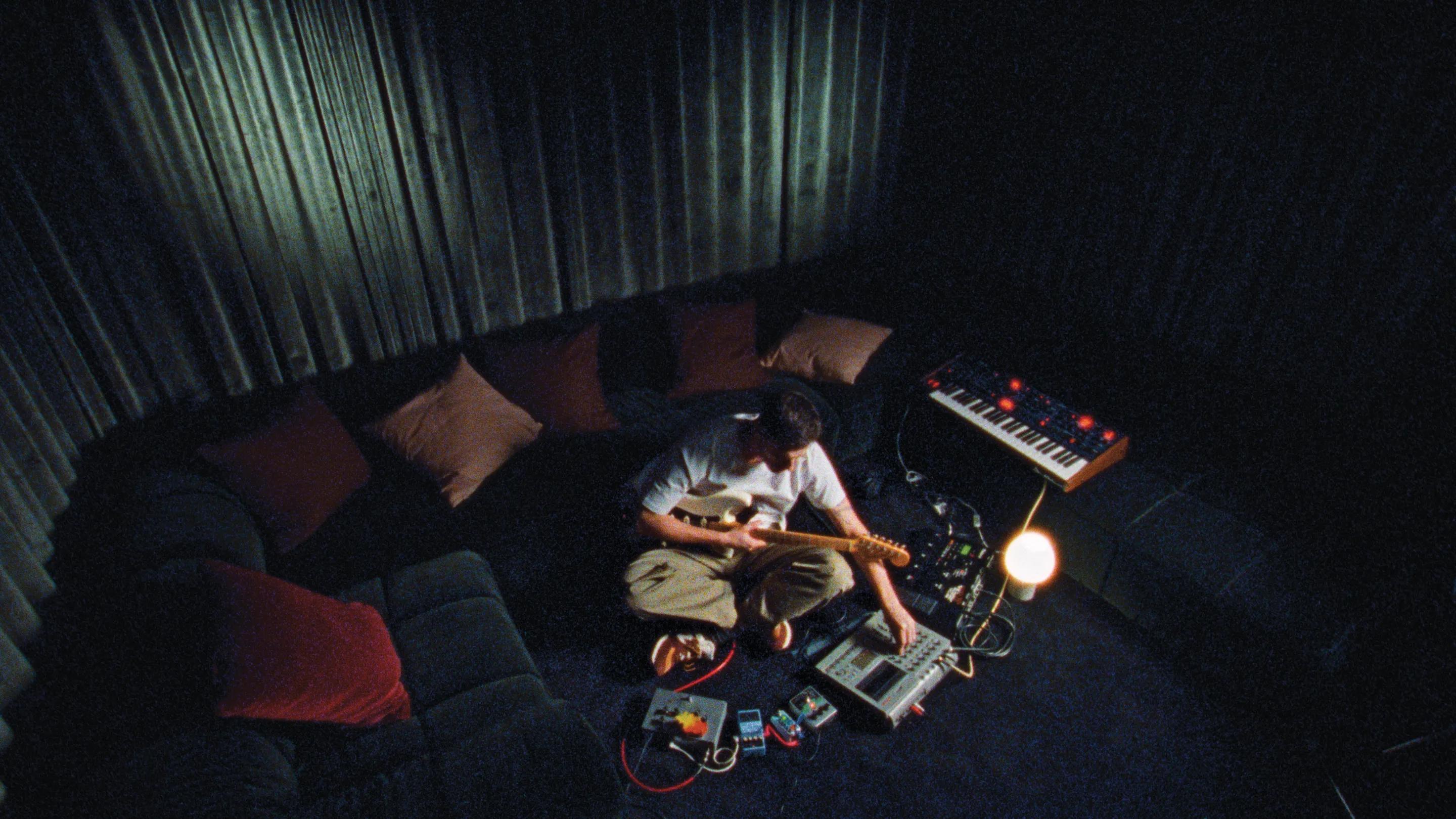 Musician playing guitar with a synthesiser in a dim lounge