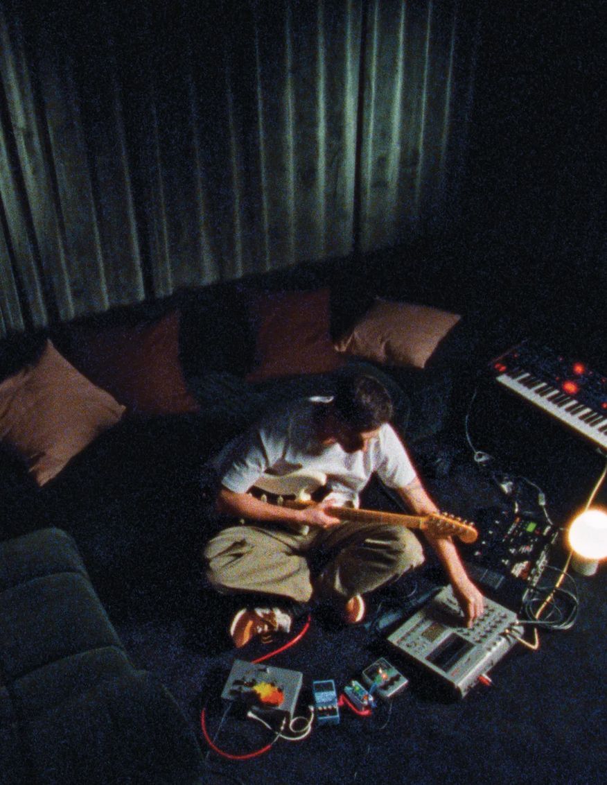 Musician playing guitar with a synthesiser in a dim lounge