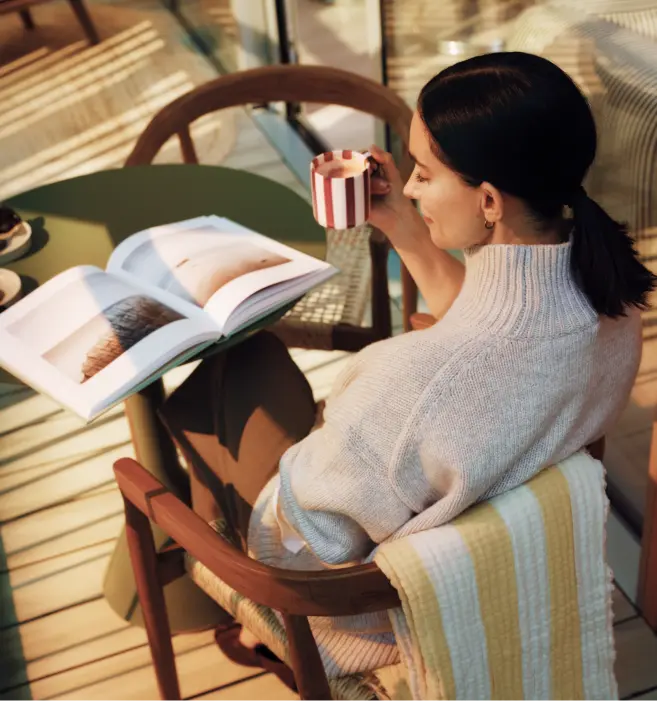 Woman reading with a coffee in a chair by the window