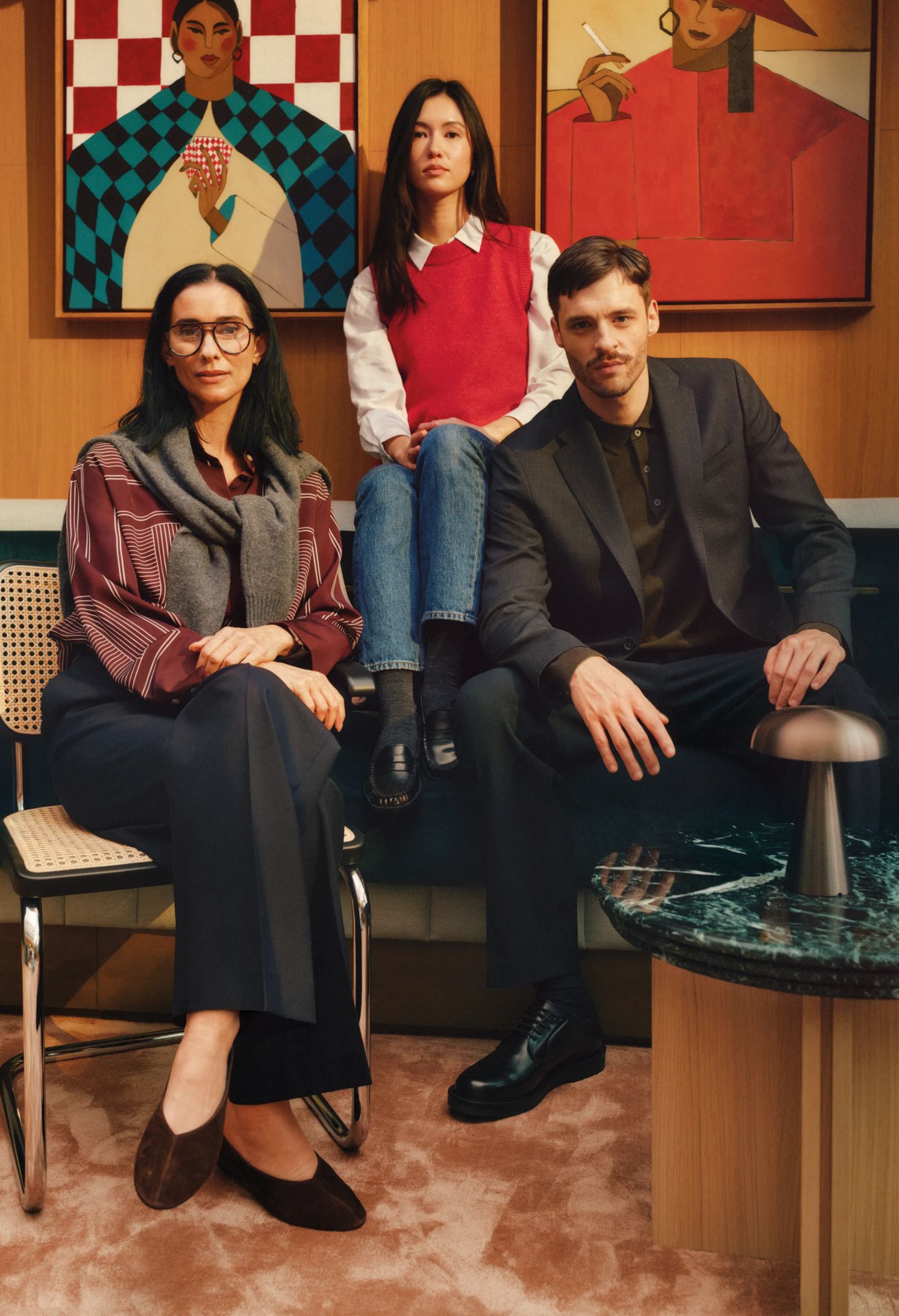 Three residents seated in a lounge below bold framed artwork