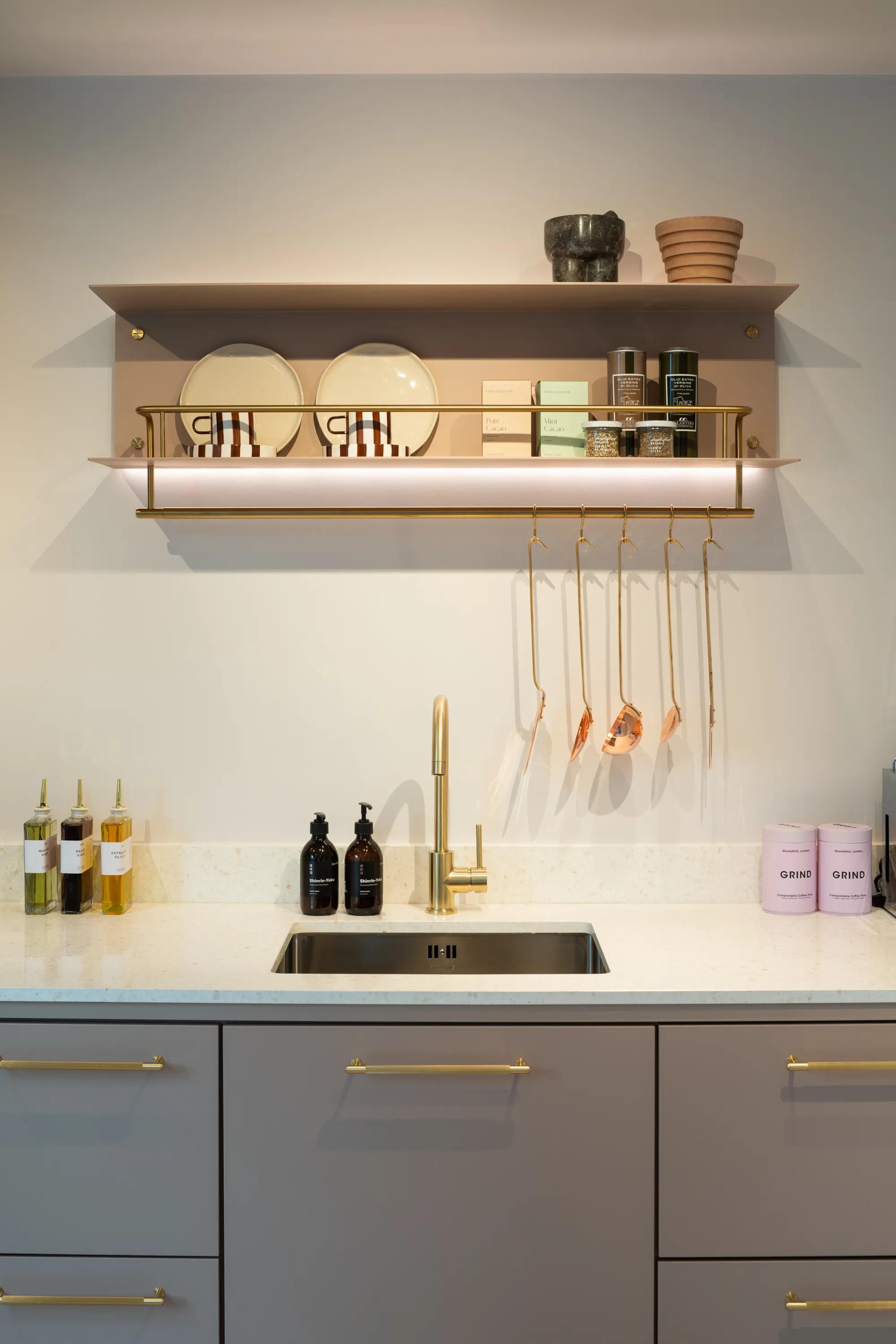 Kitchen with brass shelf rail, tap and grey cabinet fronts