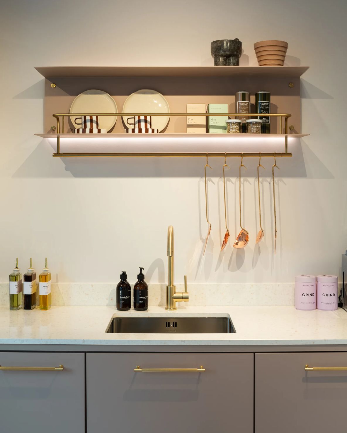 Kitchen with brass shelf rail, tap and grey cabinet fronts