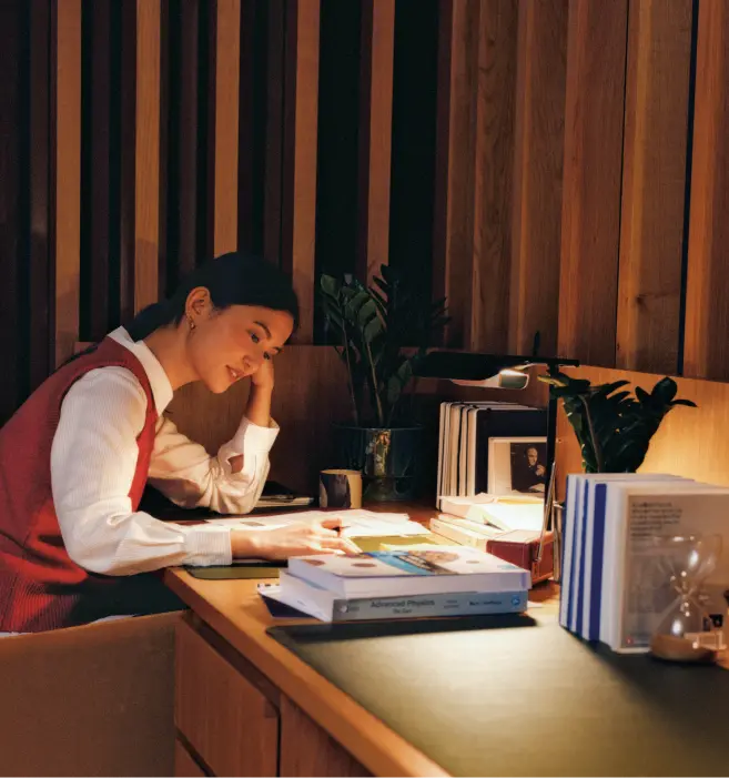 Woman studying at a desk in a warm timber booth