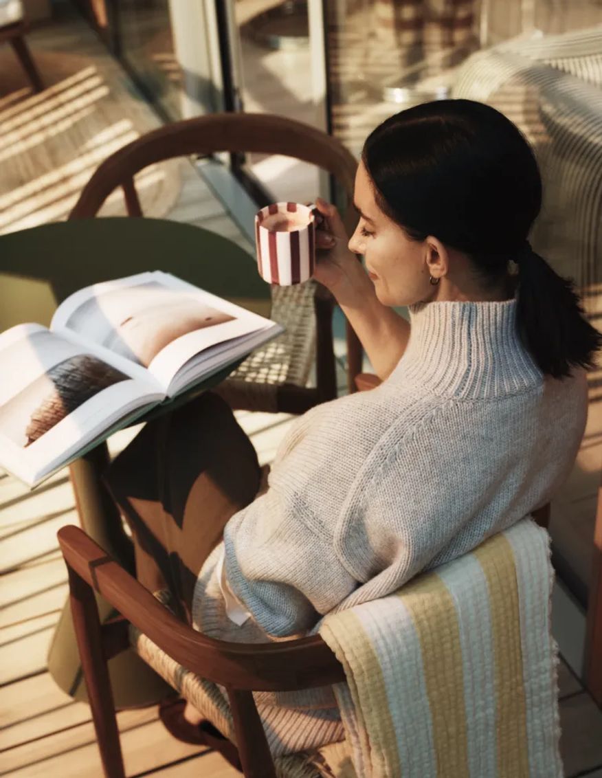 Resident reading a magazine with coffee on the balcony