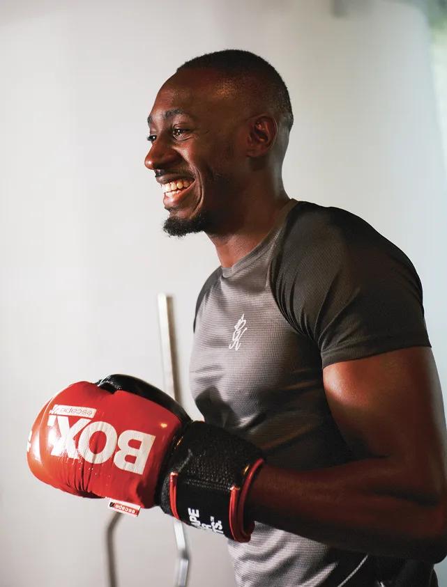 Smiling man wearing red boxing gloves after training