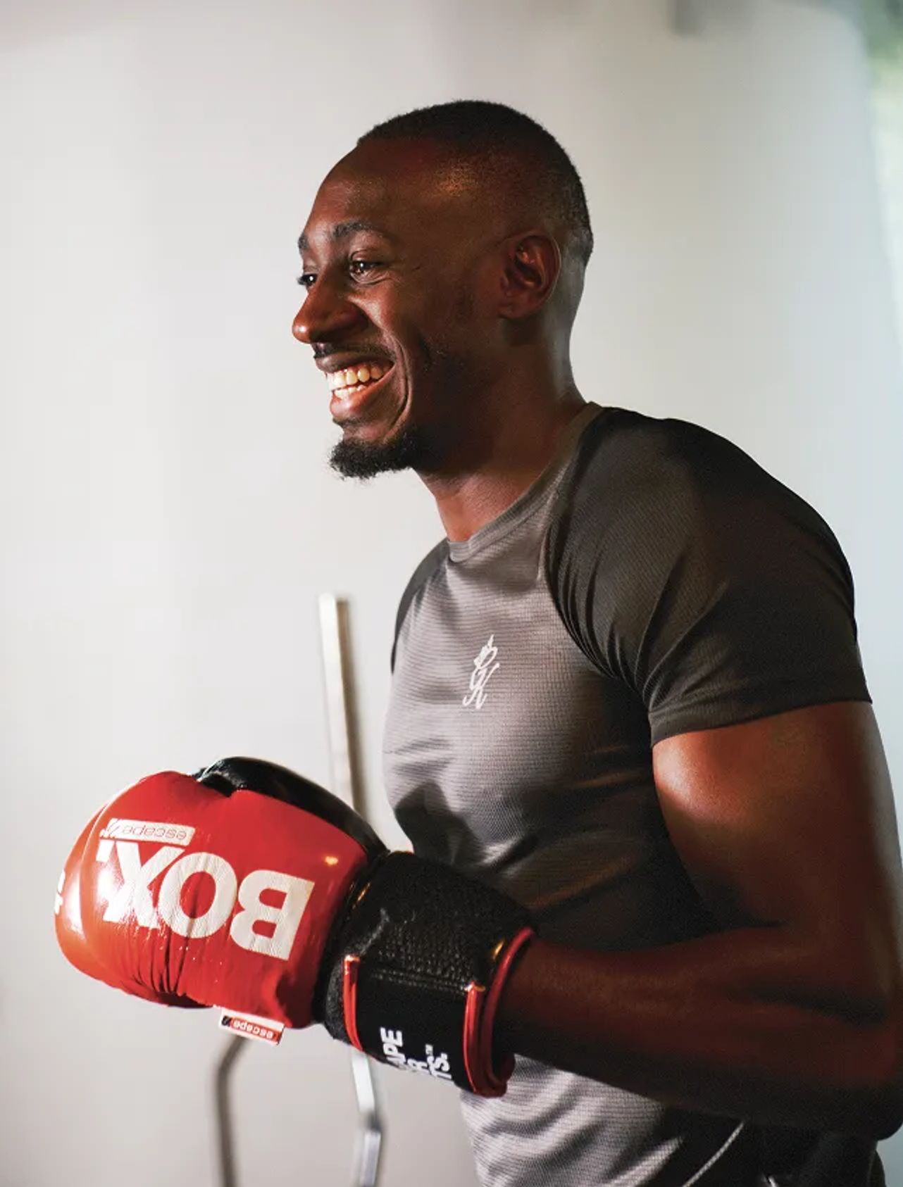 Smiling man wearing red boxing gloves after training