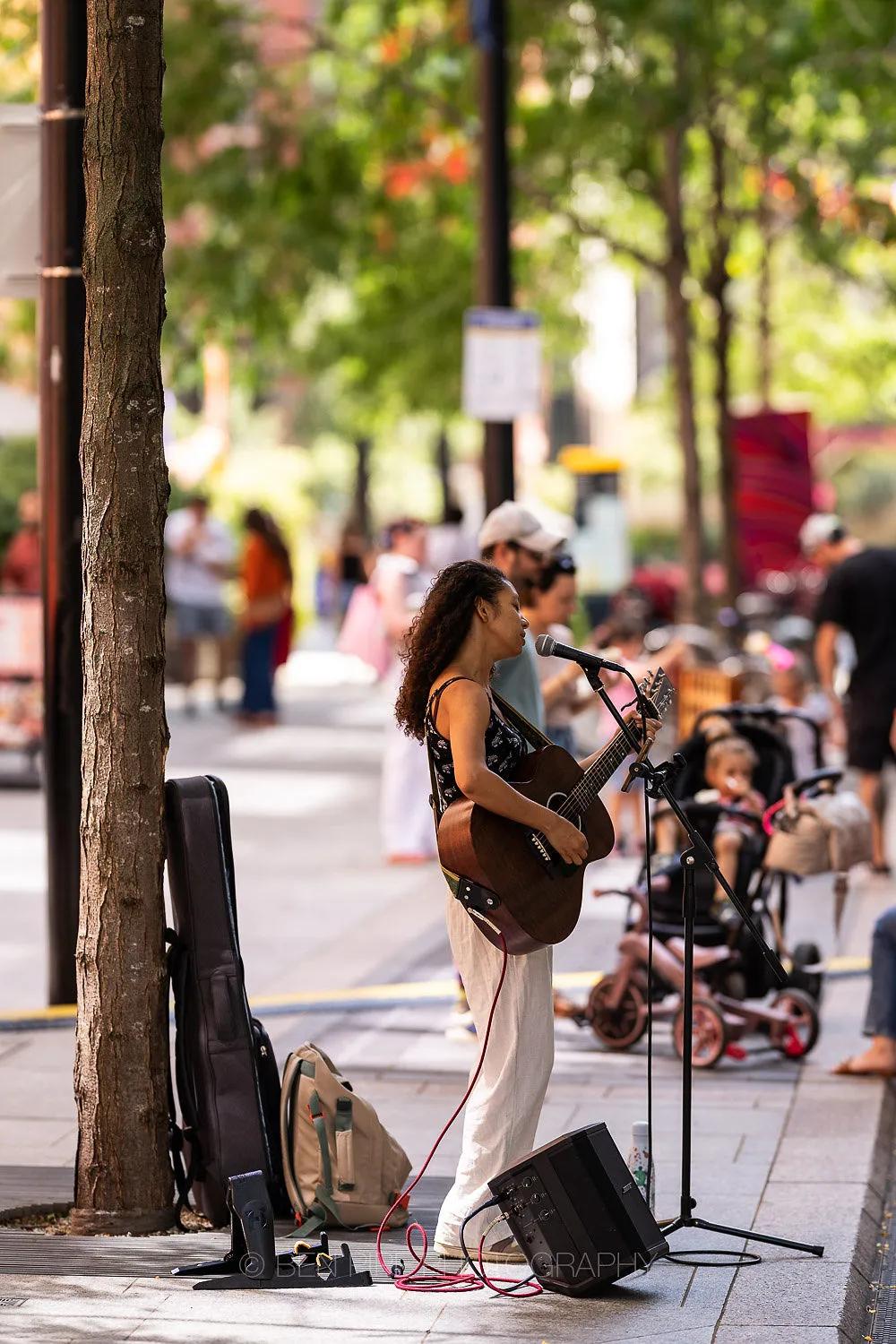 Busker singing with a guitar on a busy street