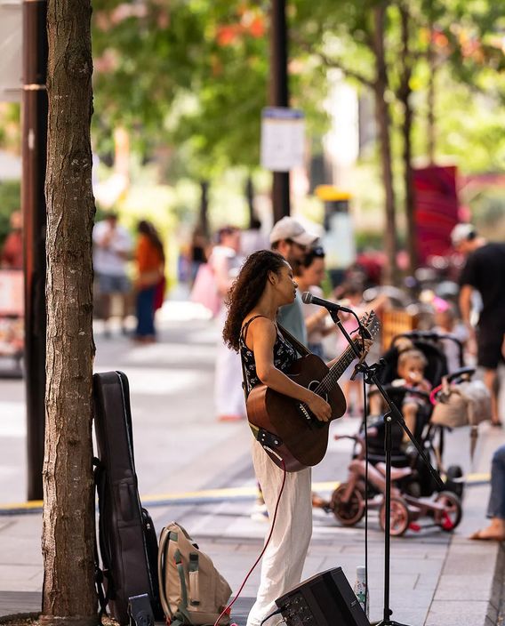 Busker singing with a guitar on a busy street