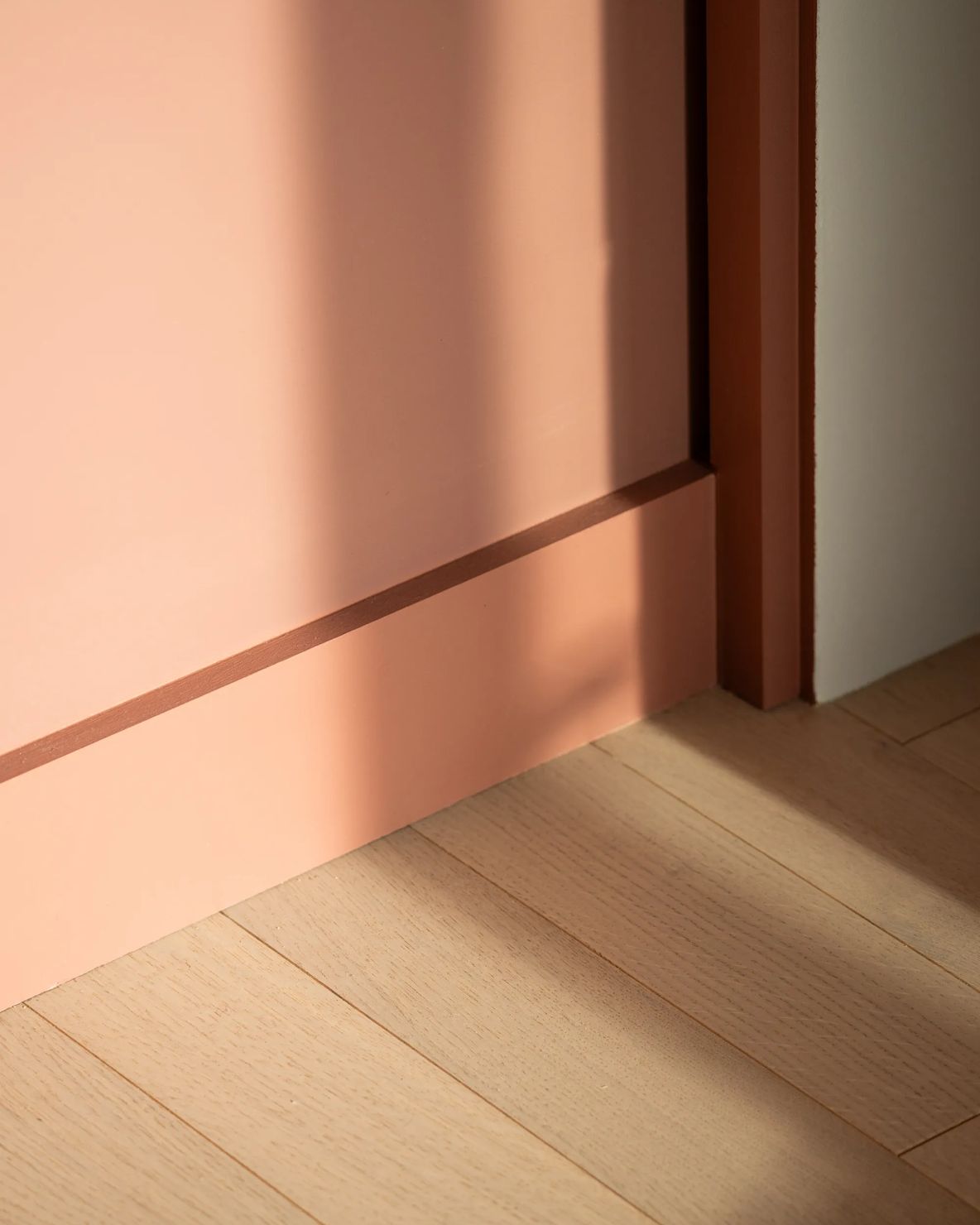 Coral painted wall meeting a timber reveal and oak floor