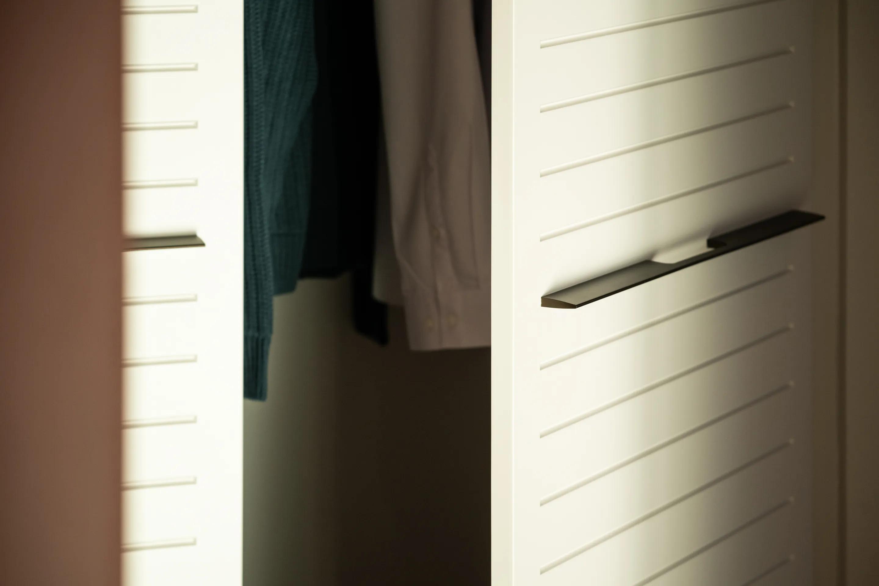 Slatted wardrobe doors open onto hanging clothes