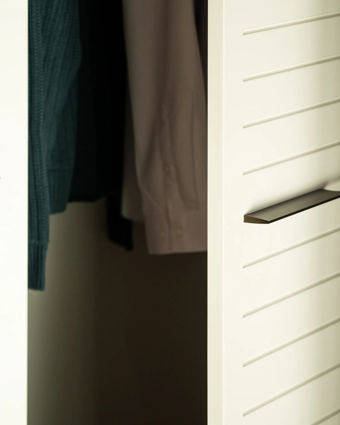 Slatted wardrobe doors open onto hanging clothes