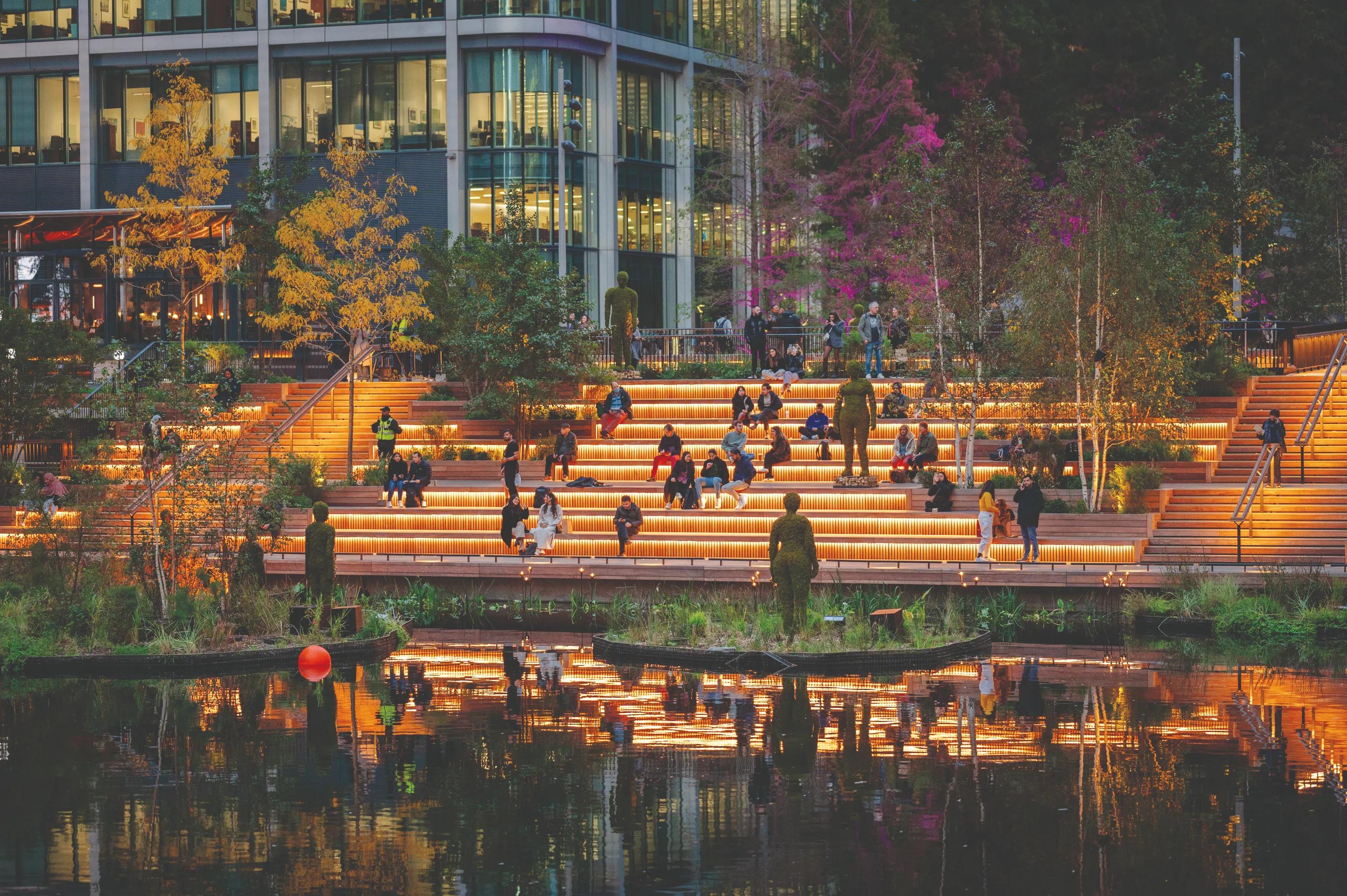 Lit waterside steps in the evening with people sitting