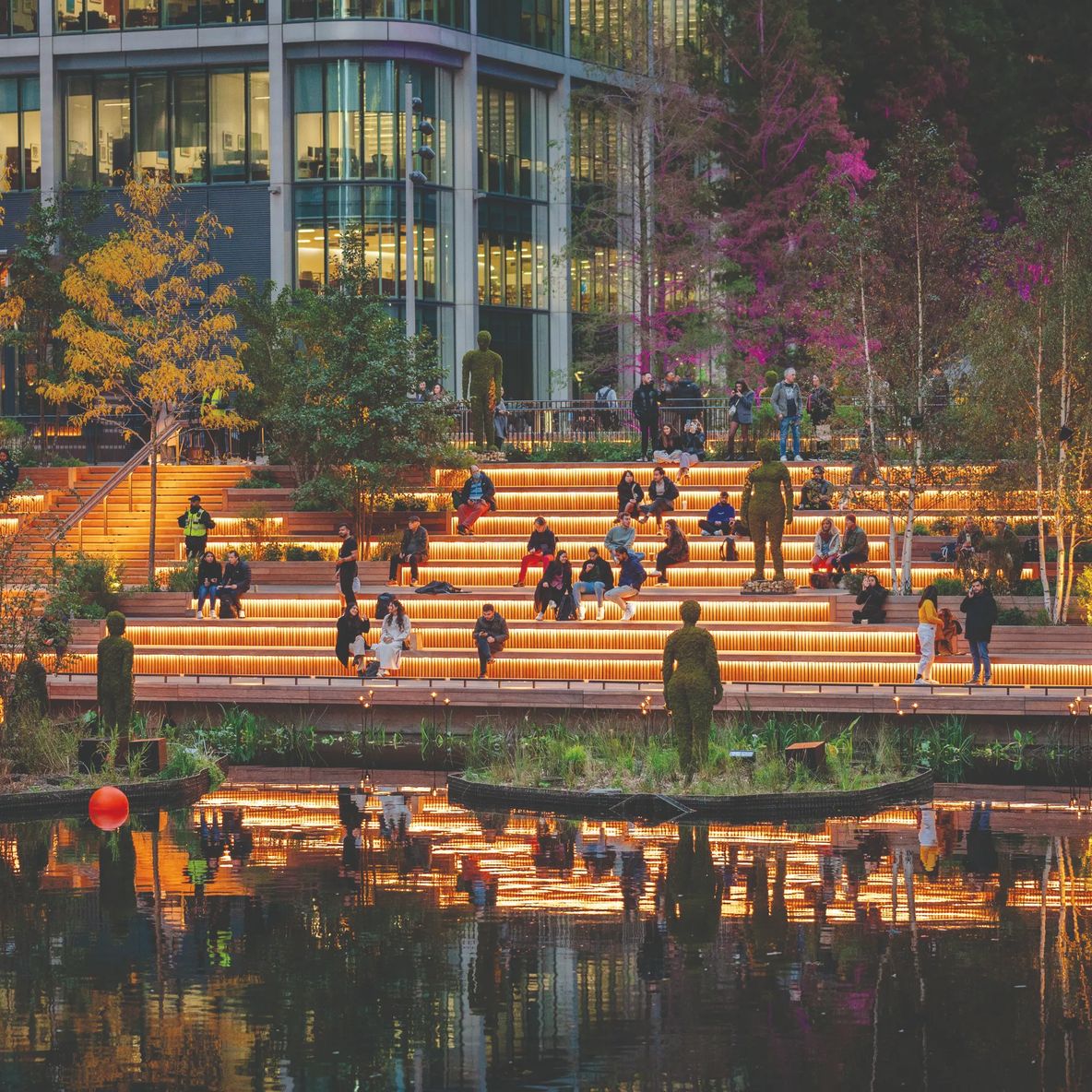 Lit waterside steps in the evening with people sitting