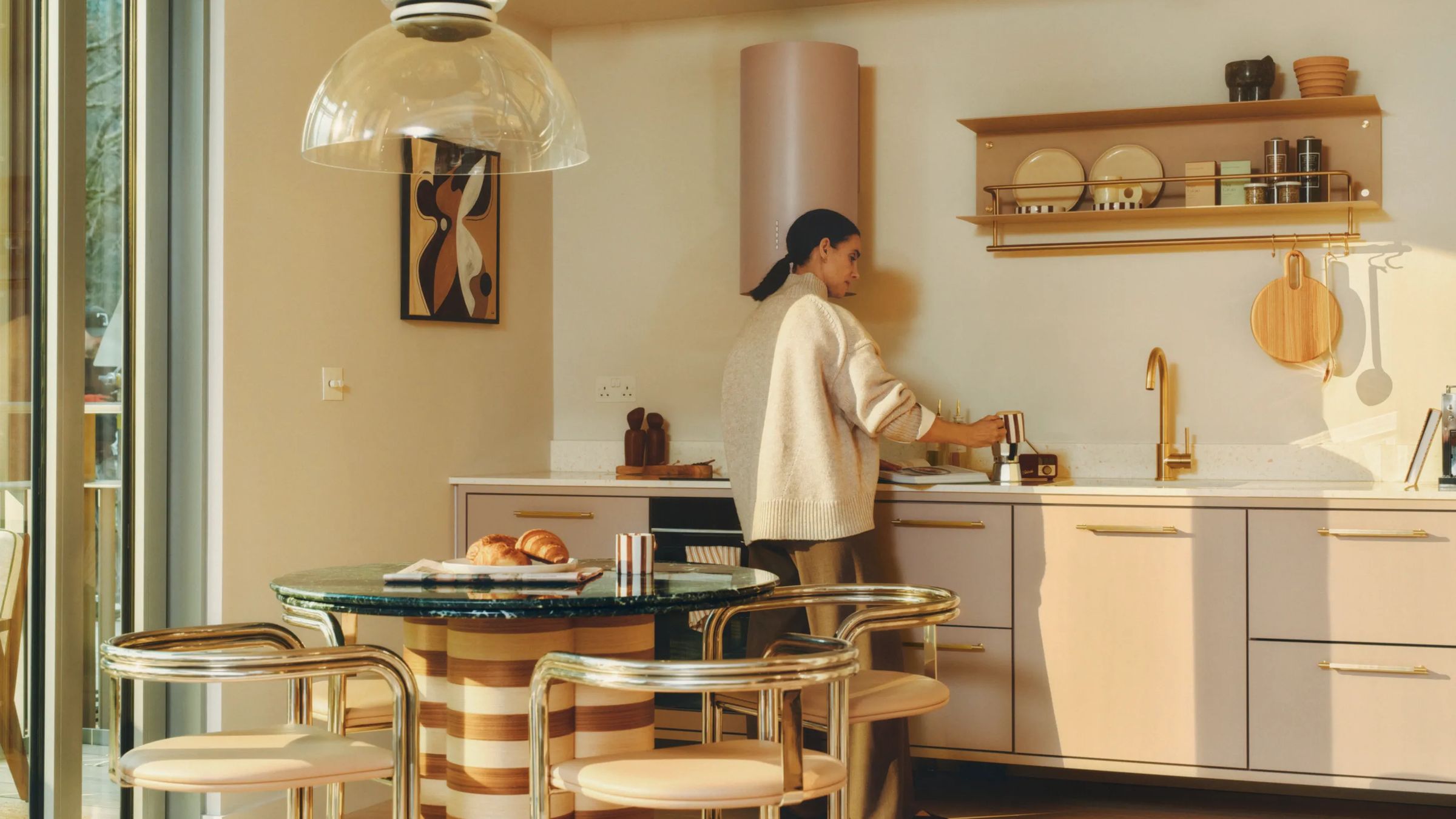 Resident cooking in a sunlit kitchen beside a round dining table