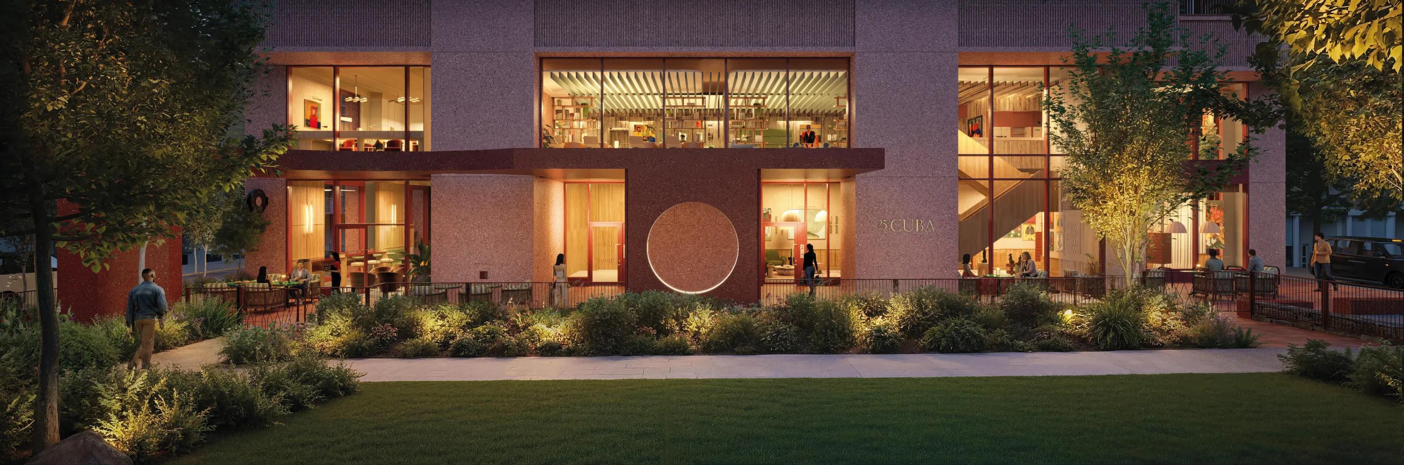 The lit lobby seen from the lawn after dark