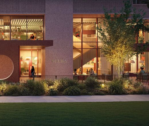 The lit lobby seen from the lawn after dark