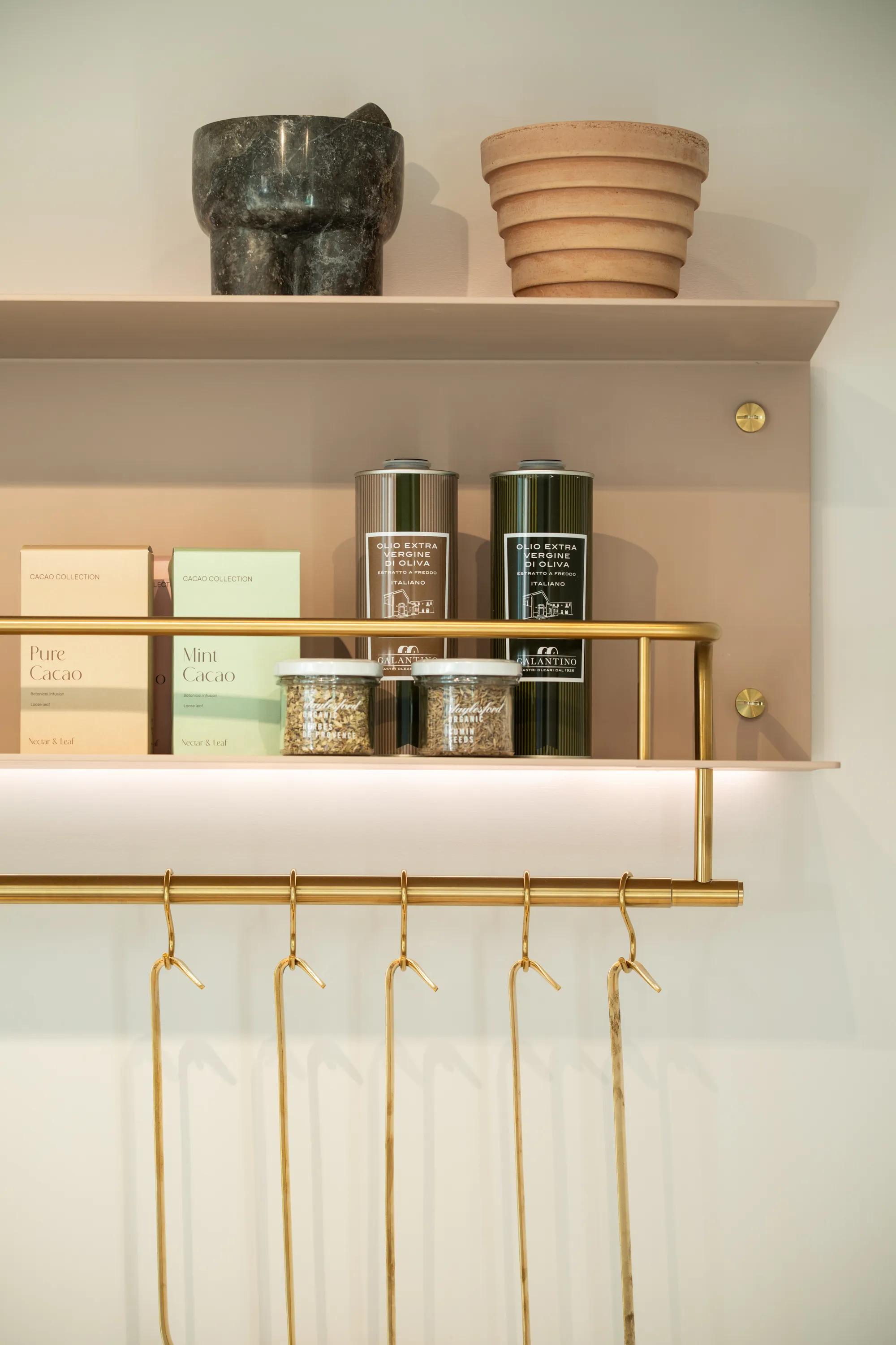 Open shelf with jars and a brass rail of hanging hooks