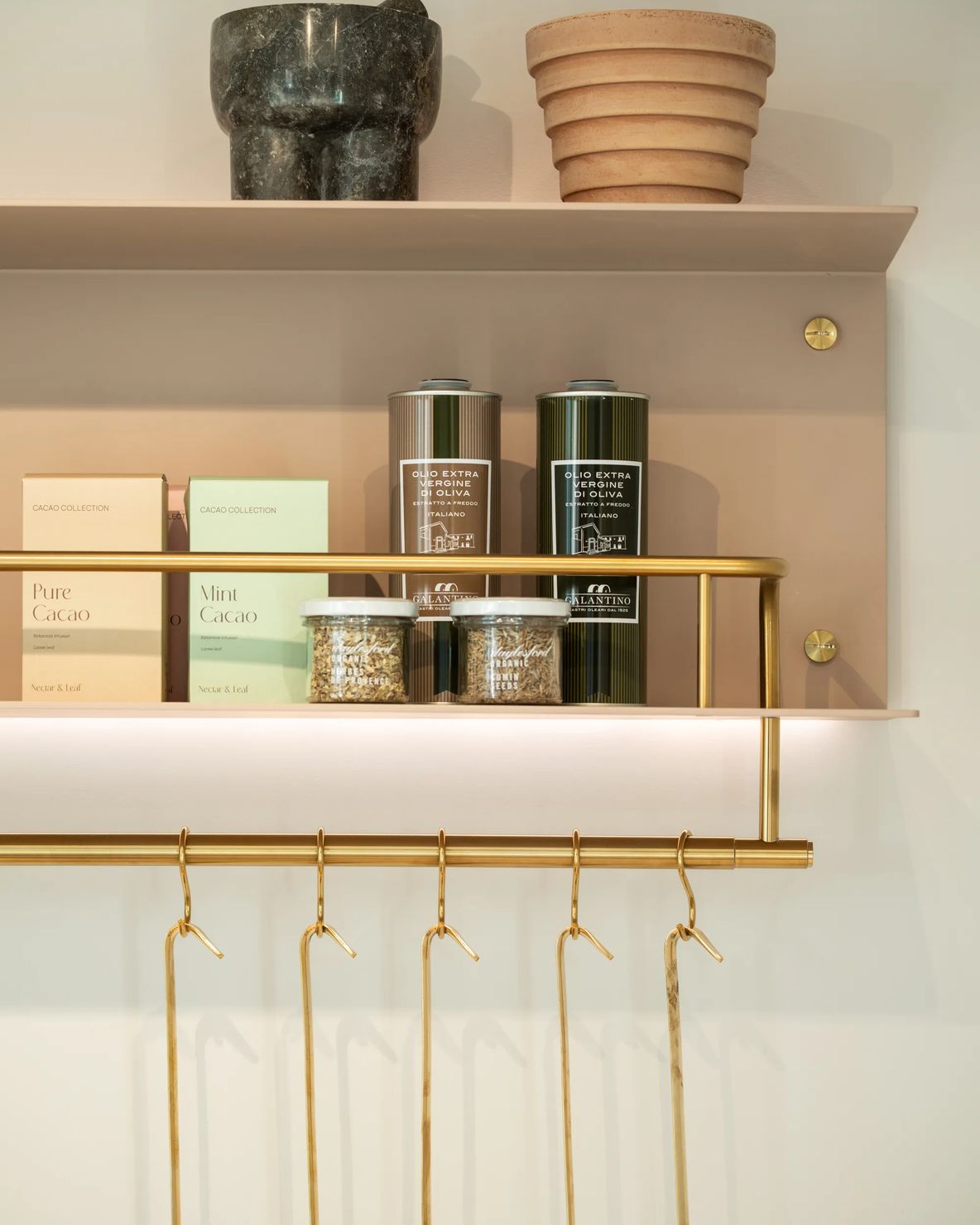 Open shelf with jars and a brass rail of hanging hooks