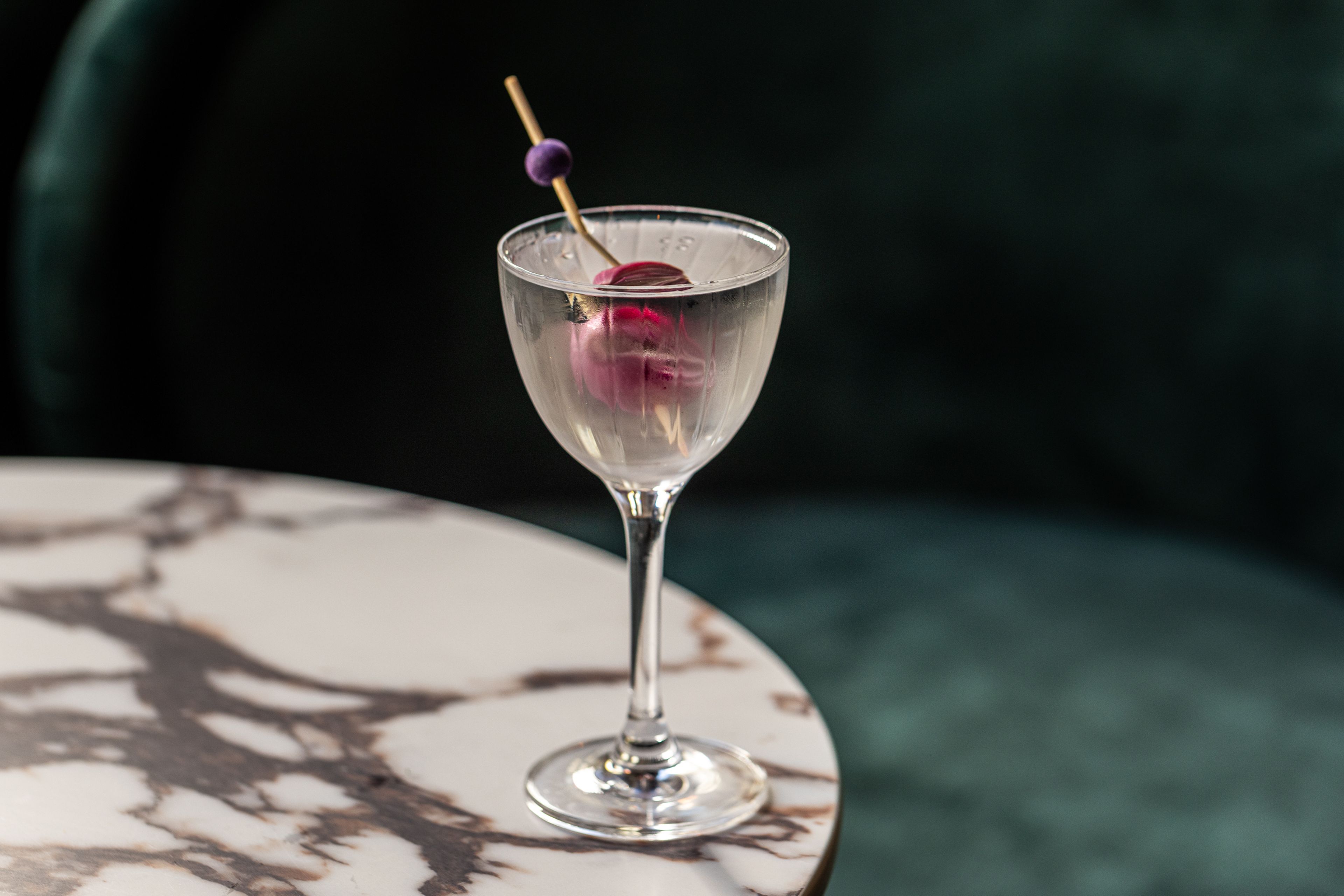 A cocktail with a pickled onion on a toothpick
