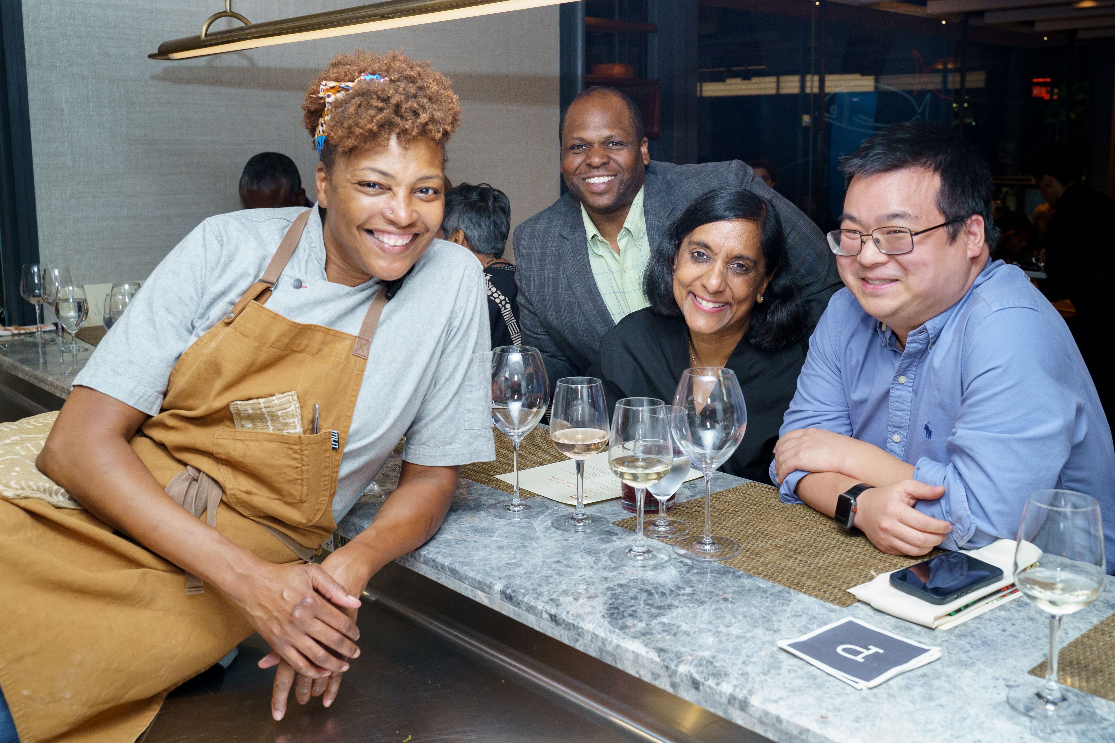 Chef leaning on counter with guests on the other side