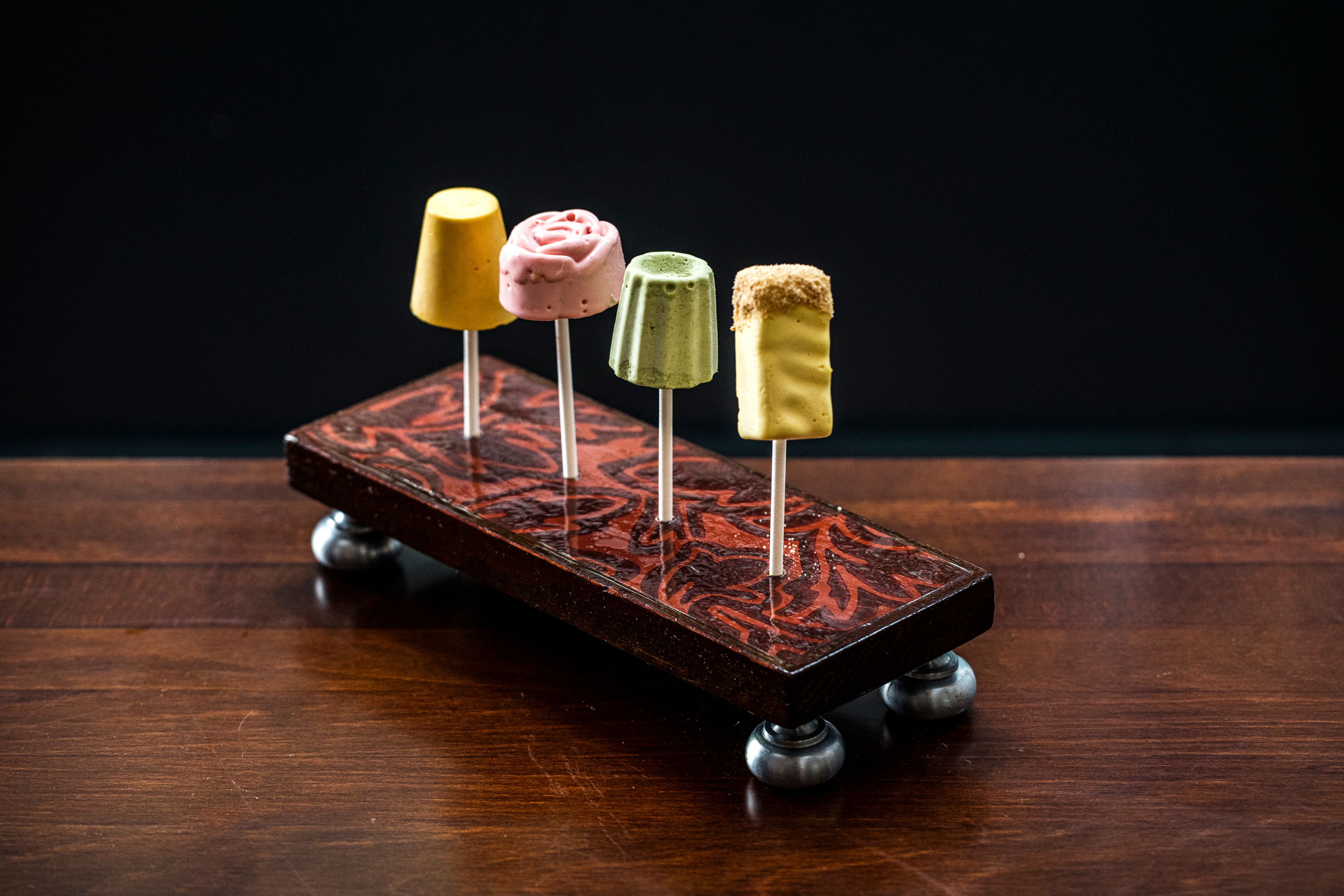 Four bite-sized desserts on sticks in a custom enamel stand
