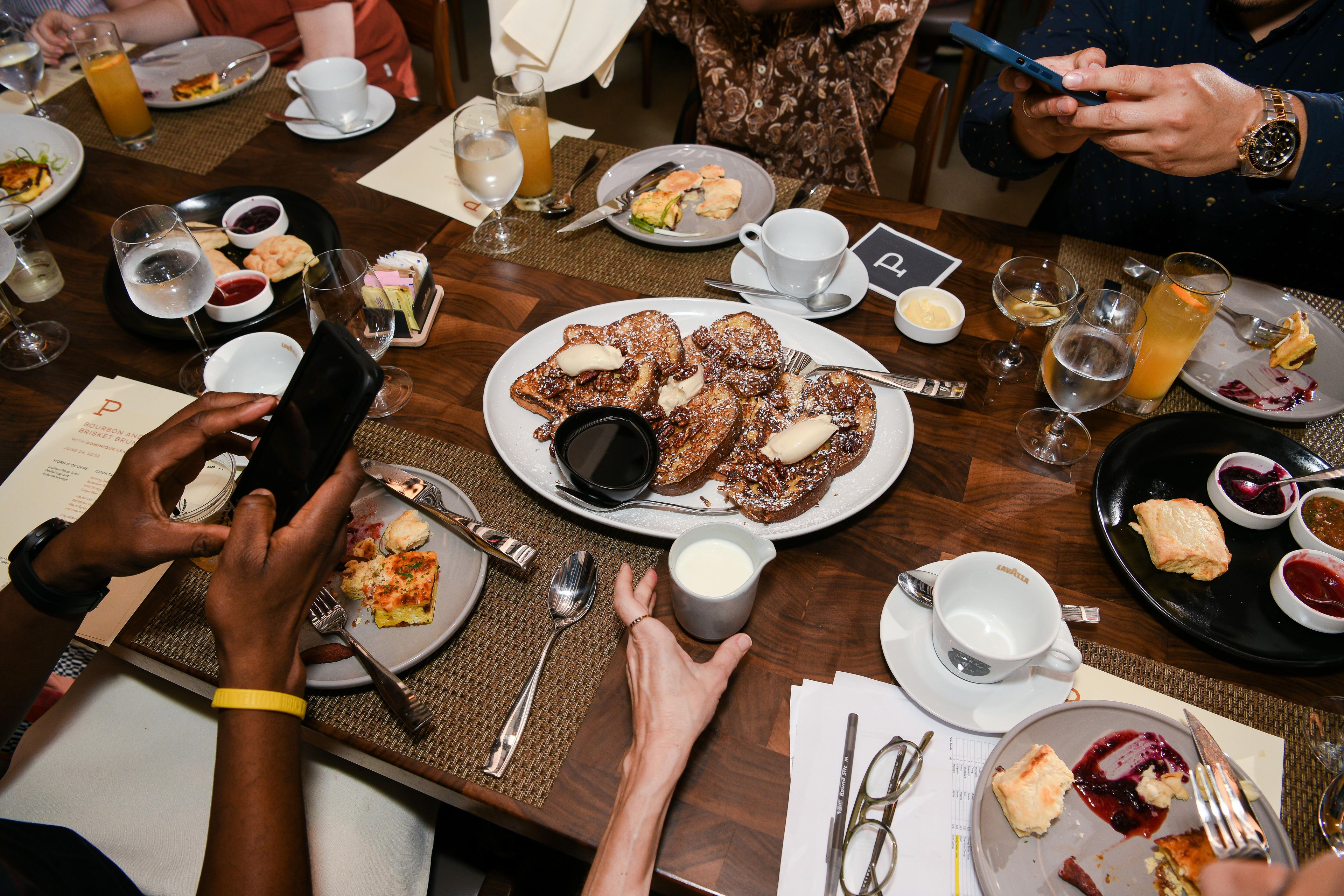 Overhead shot of people taking pictures of french toast on a table