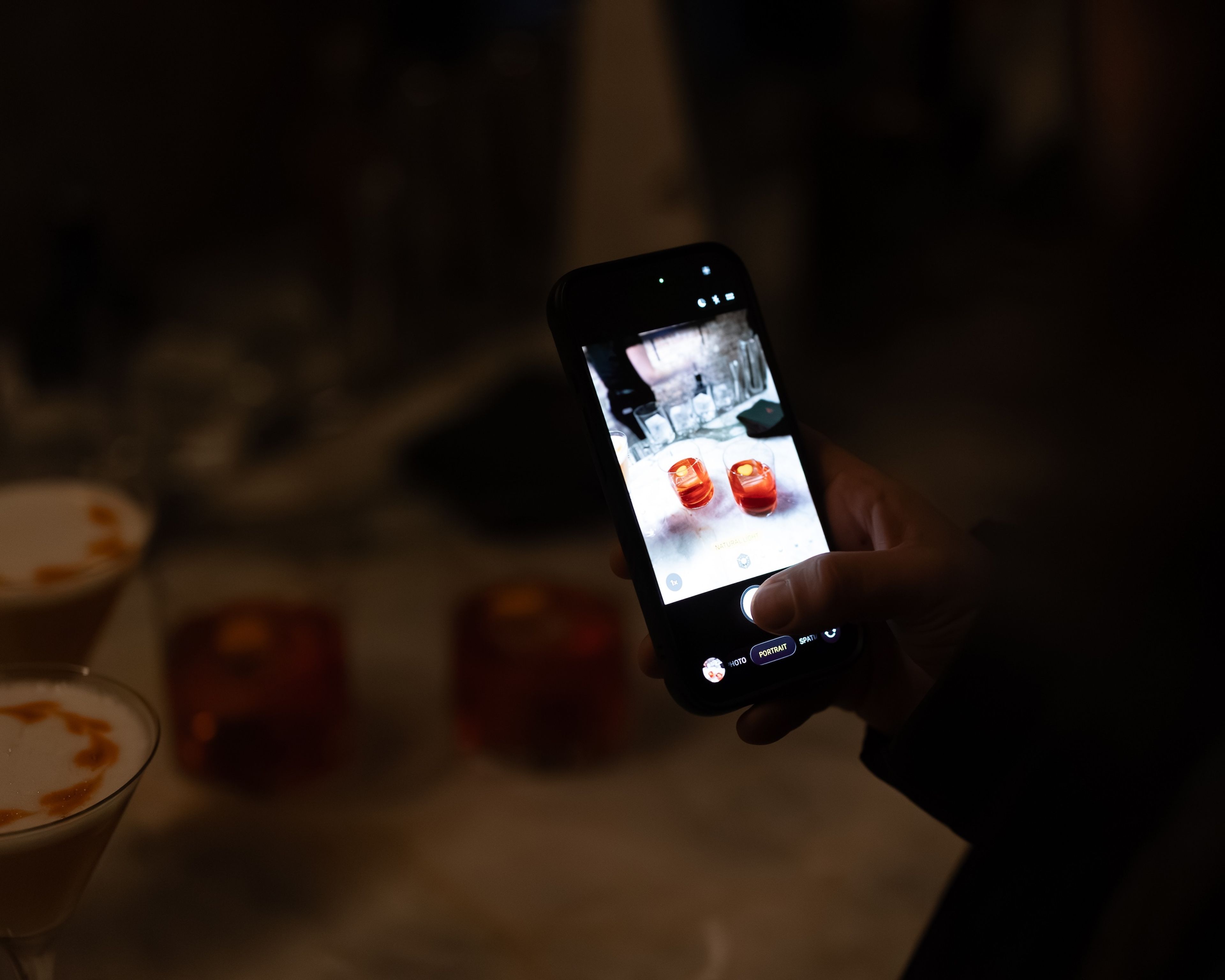 A person takes a photo of two cocktails on their phone