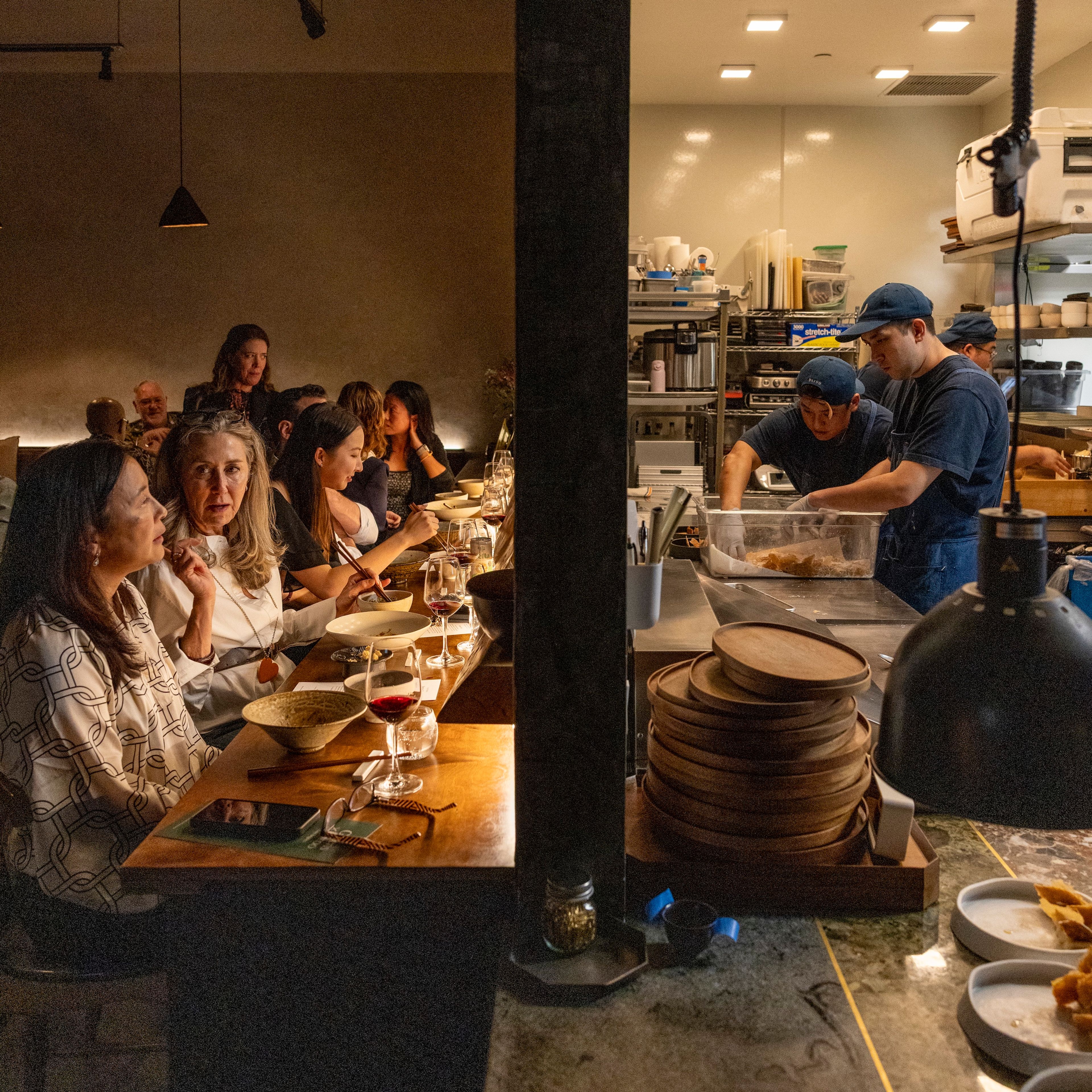A row of diners and kitchen staff separated by a wall
