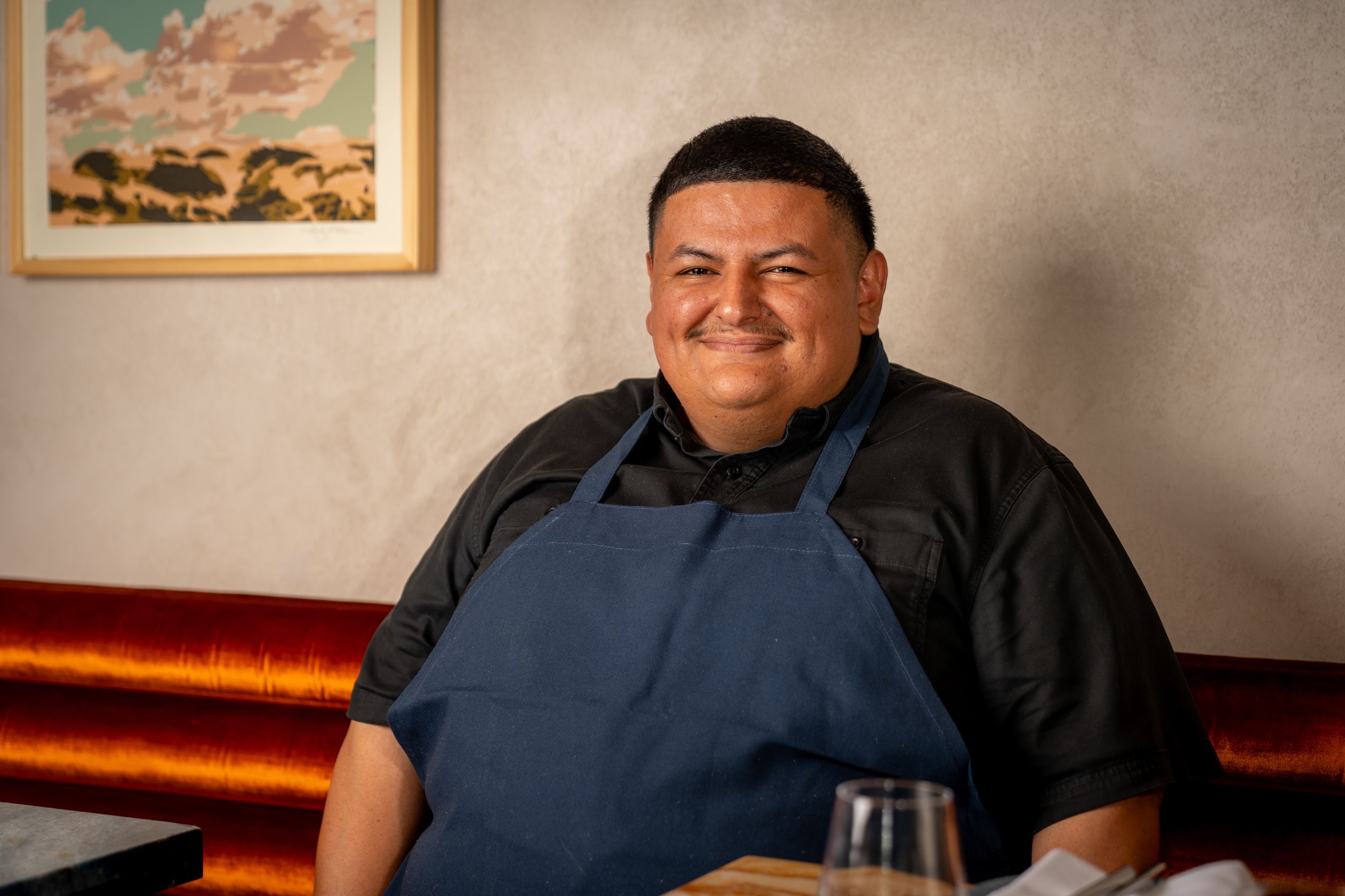 Adrian Torres smiling at a restaurant booth