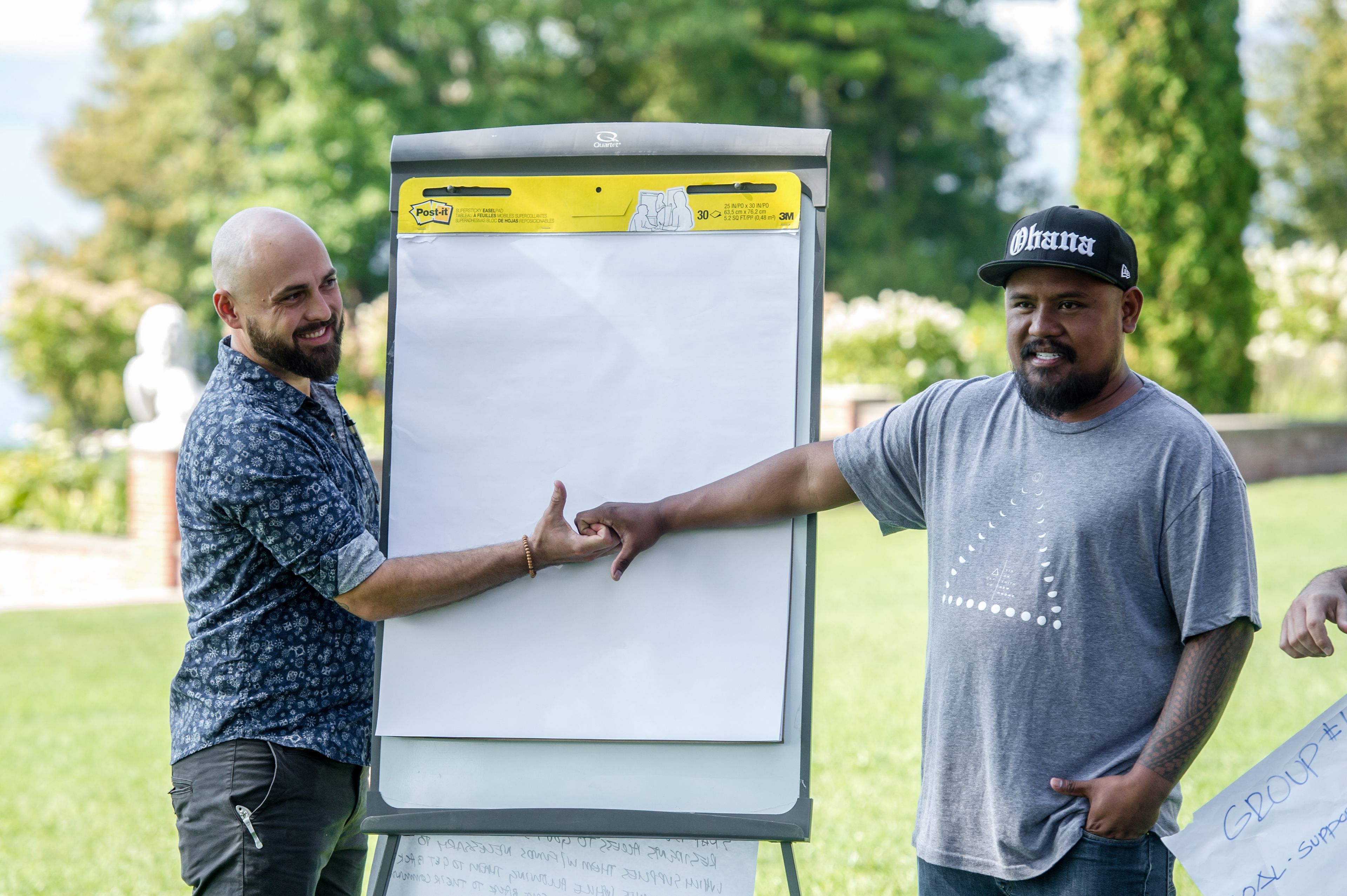 Two men holding hands standing in front of an easel