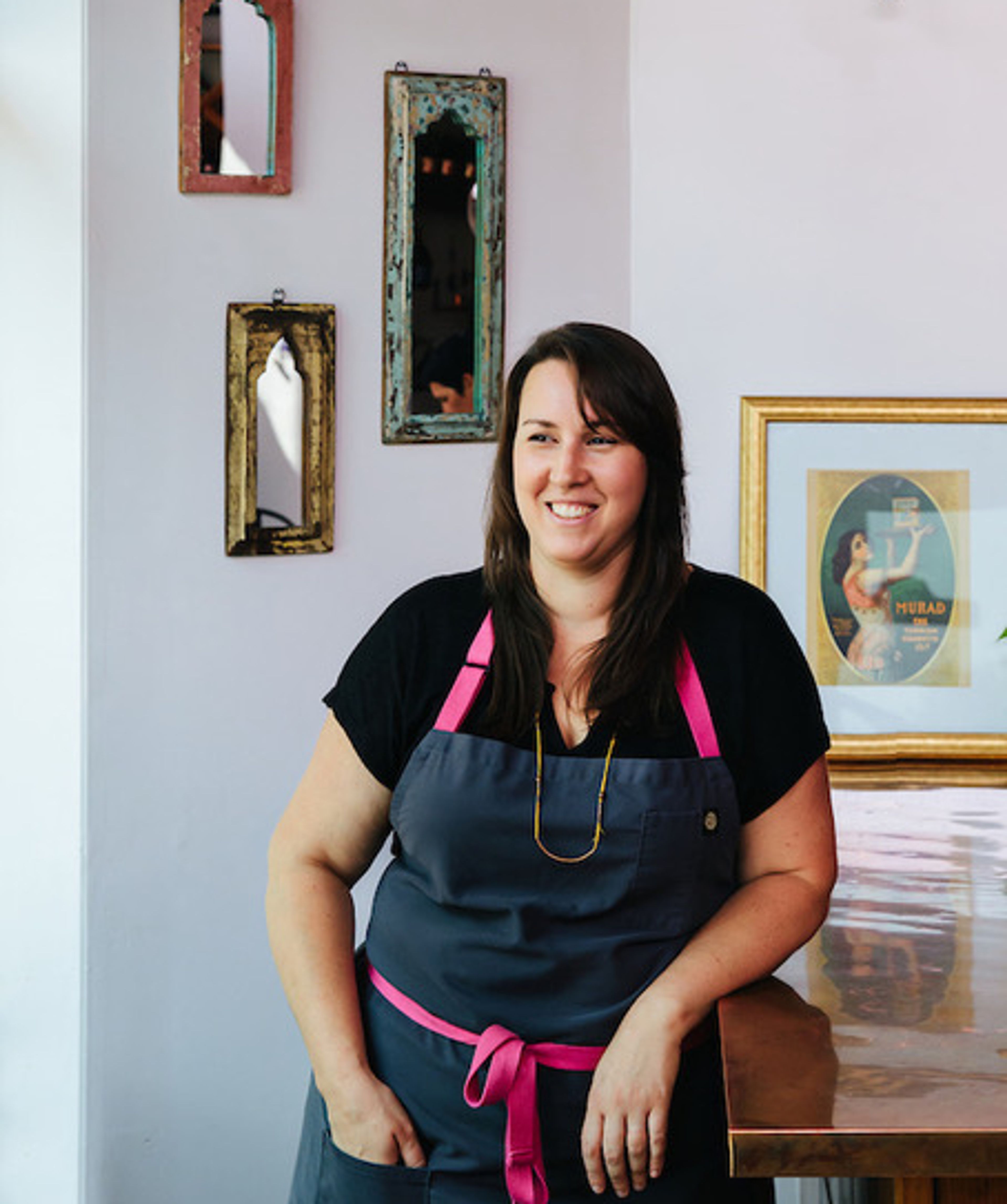 Cara Tobin in a chef apron standing by a wooden bar top