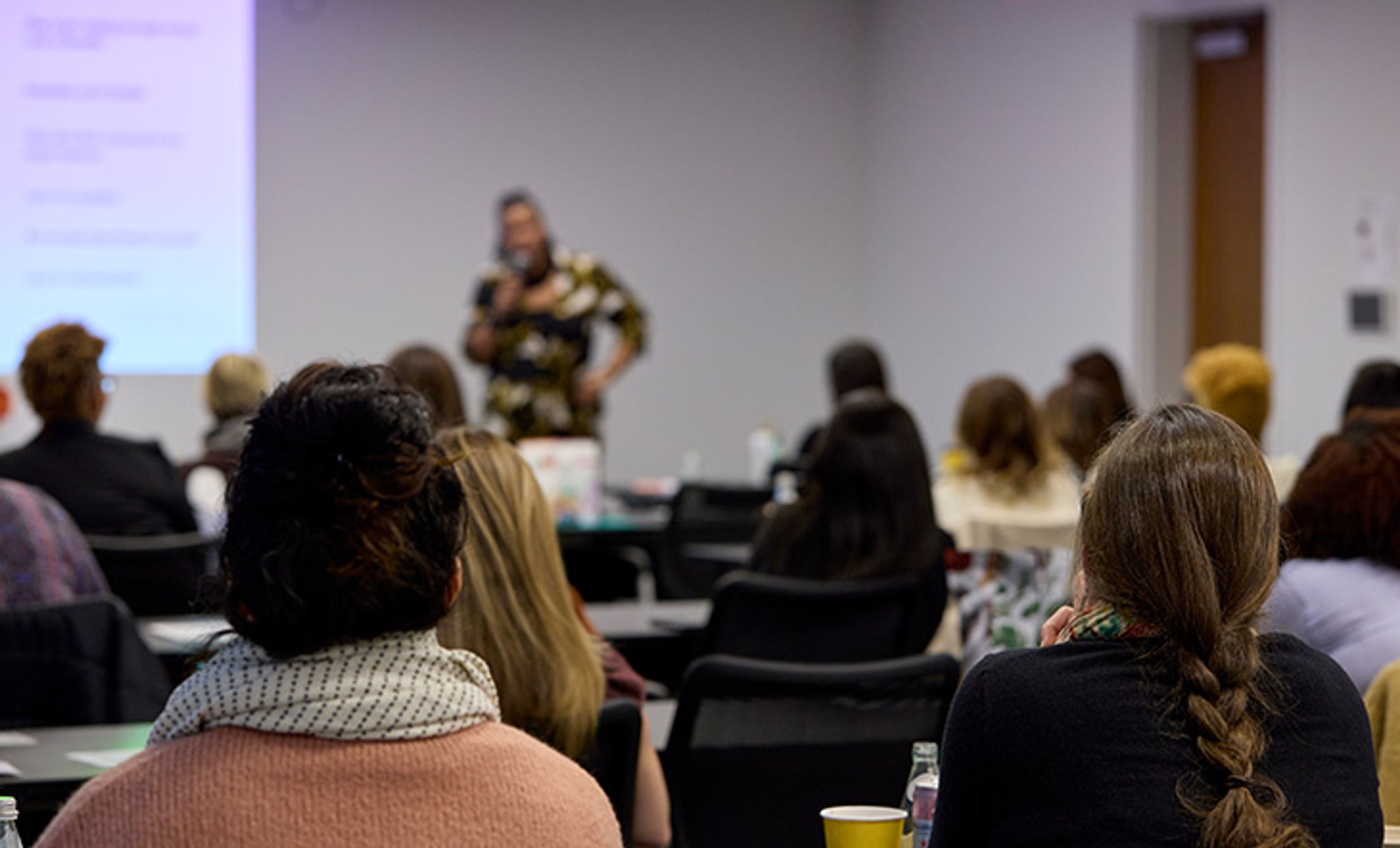 Back of two women's heads looking at a presentation at the front of the room