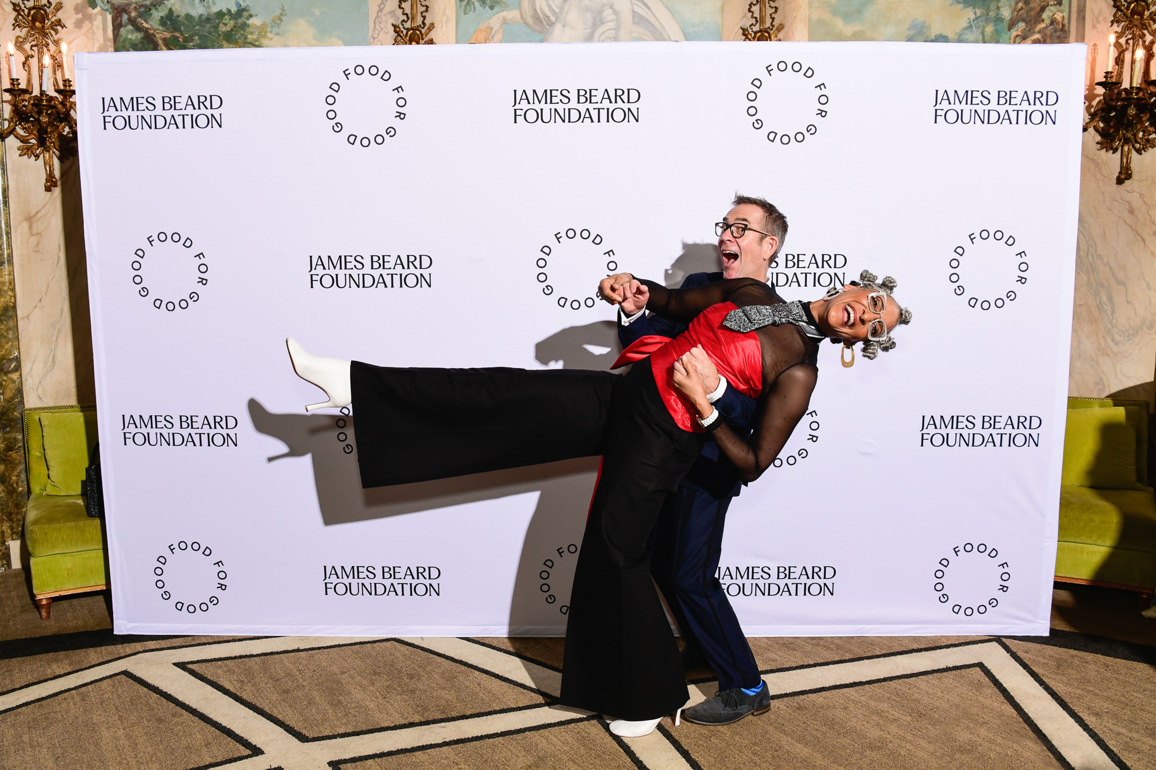 Man dipping woman in front of step and repeat