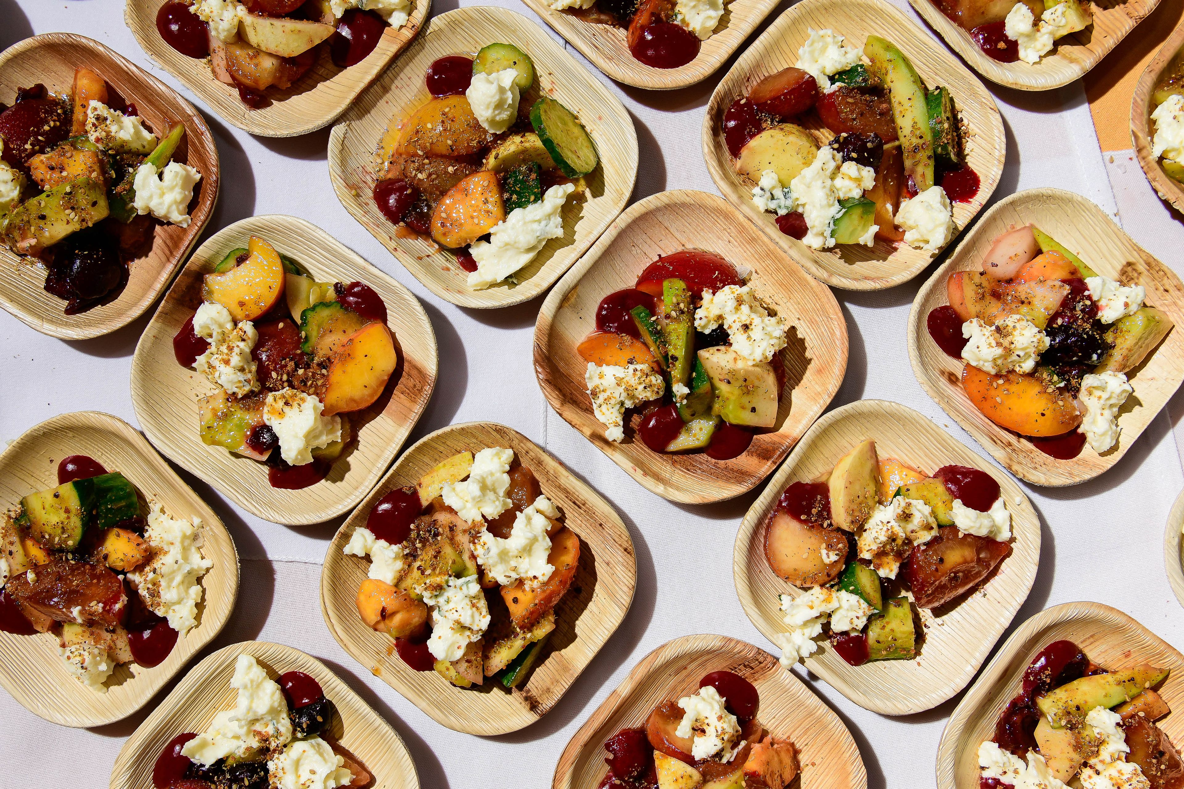 Canapes of ricotta, cucumbers, and stone fruit on bamboo plates