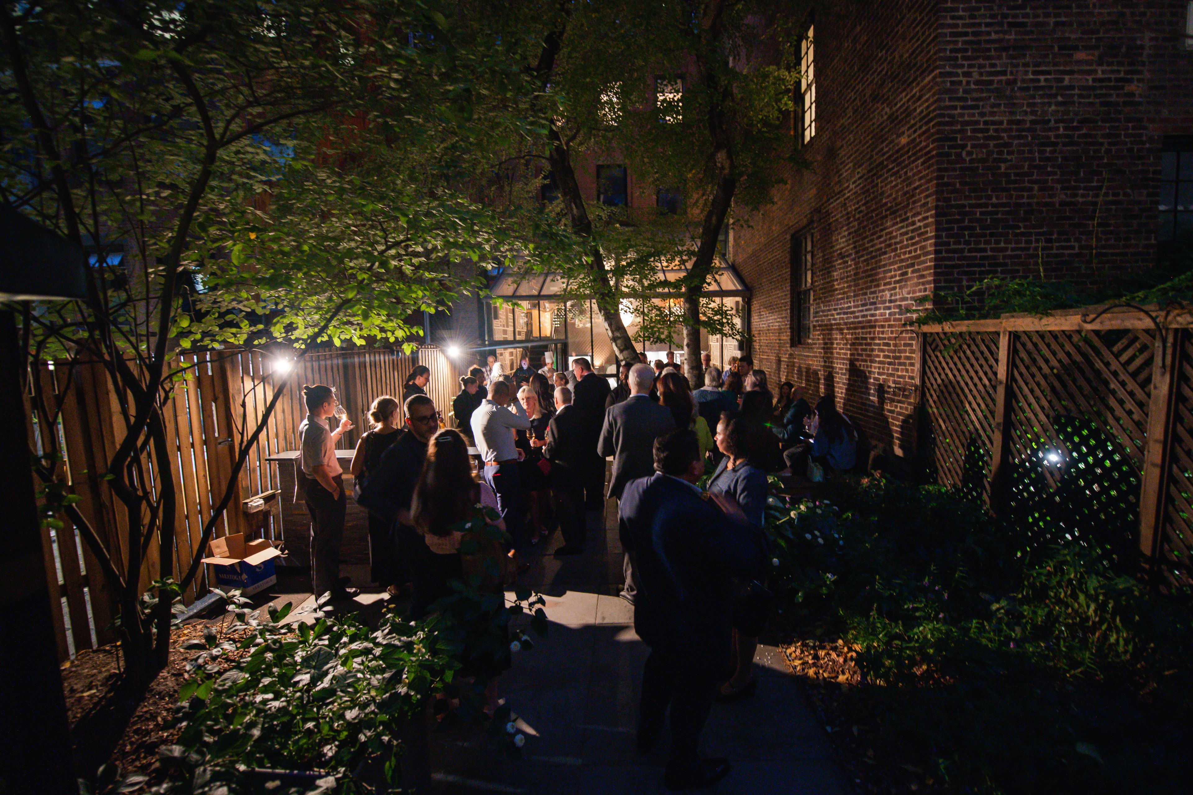 People standing in a garden behind an NYC townhouse