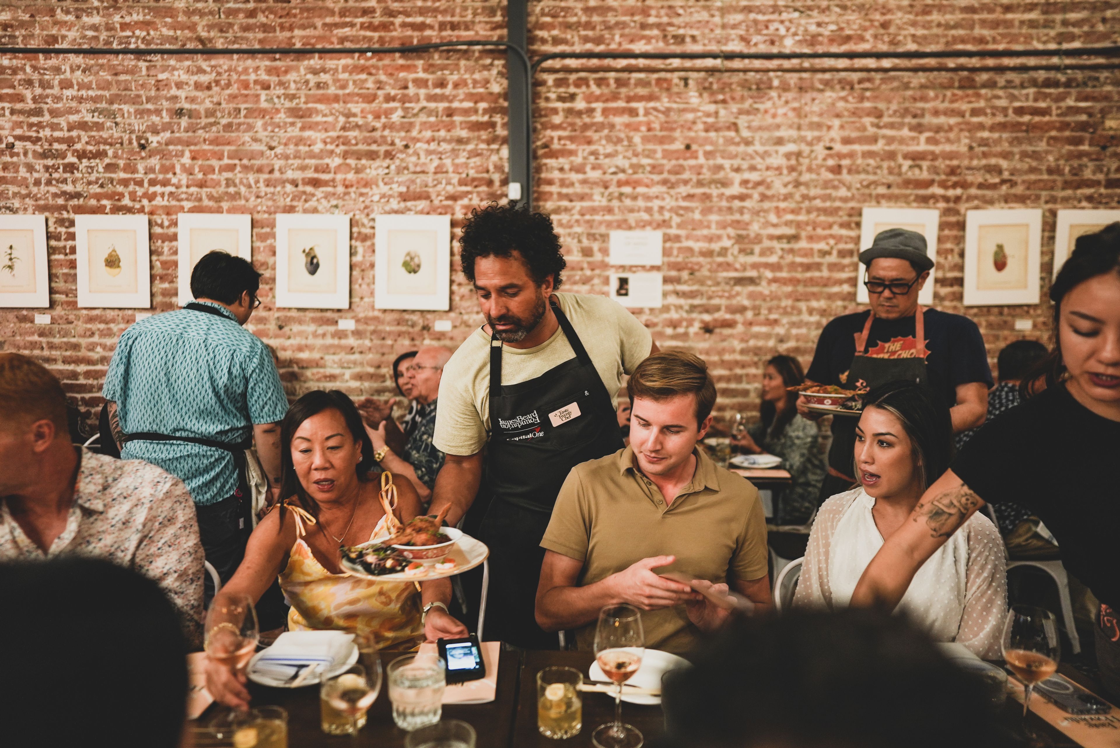 Diners being served food by chef in black apron