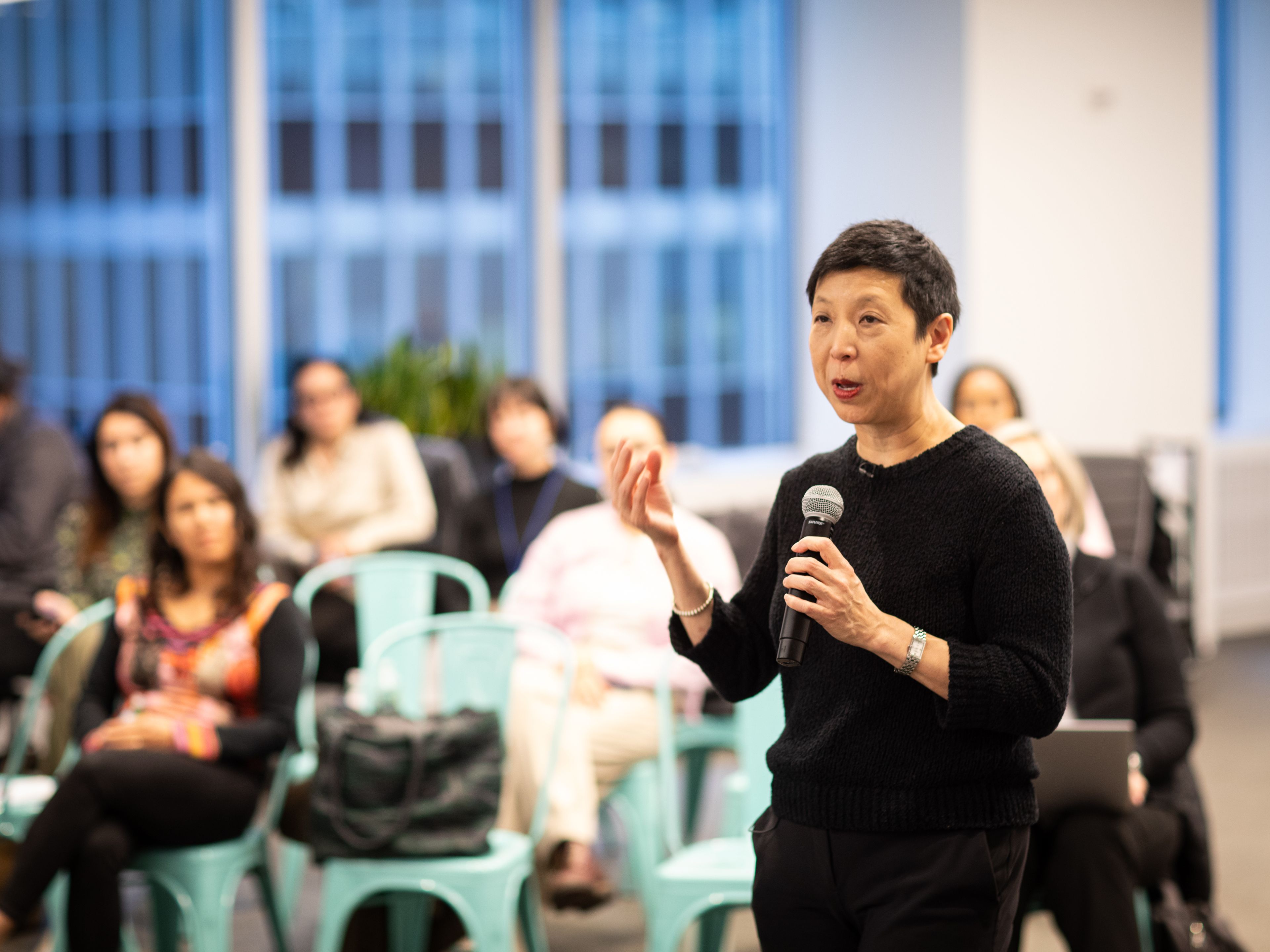 Woman in all black speaking into a microphone