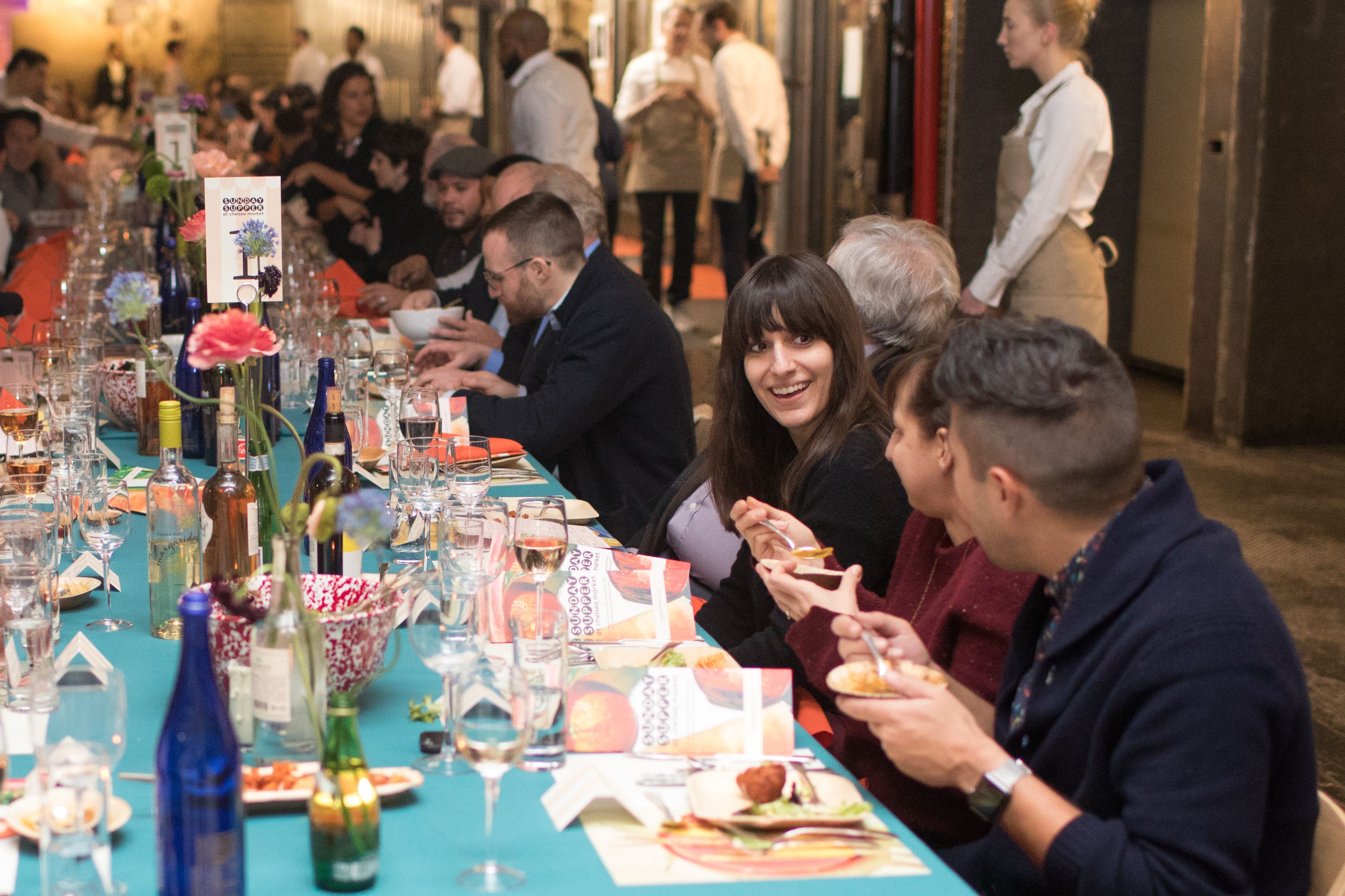 People sitting at a long communal table enjoying a meal